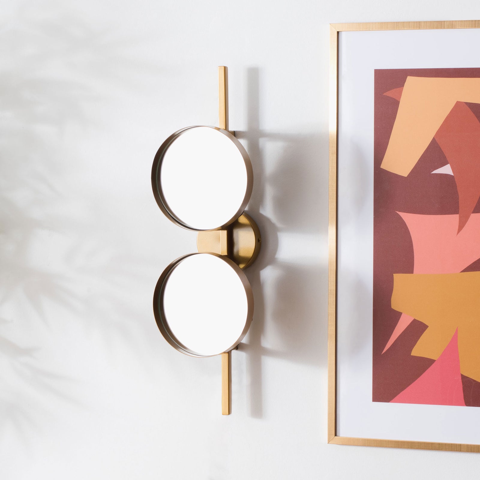 Two round mirrors on a slender gold bar add sculptural symmetry to a bright wall. || MRR3073A || front_angle_room
