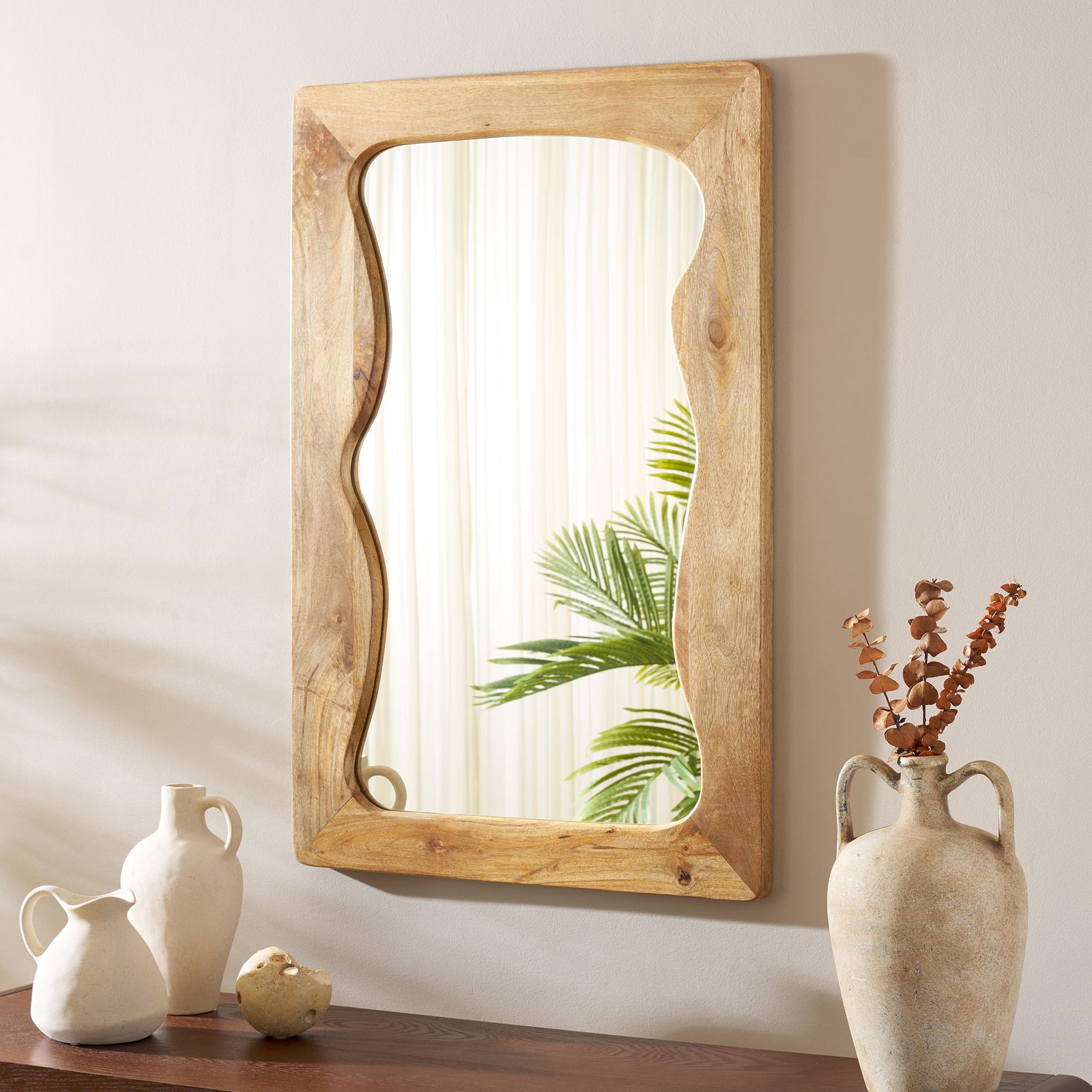 A wall-mounted mirror with a sculpted wood frame brings natural warmth above a console || MRR4005A || front_angle_room