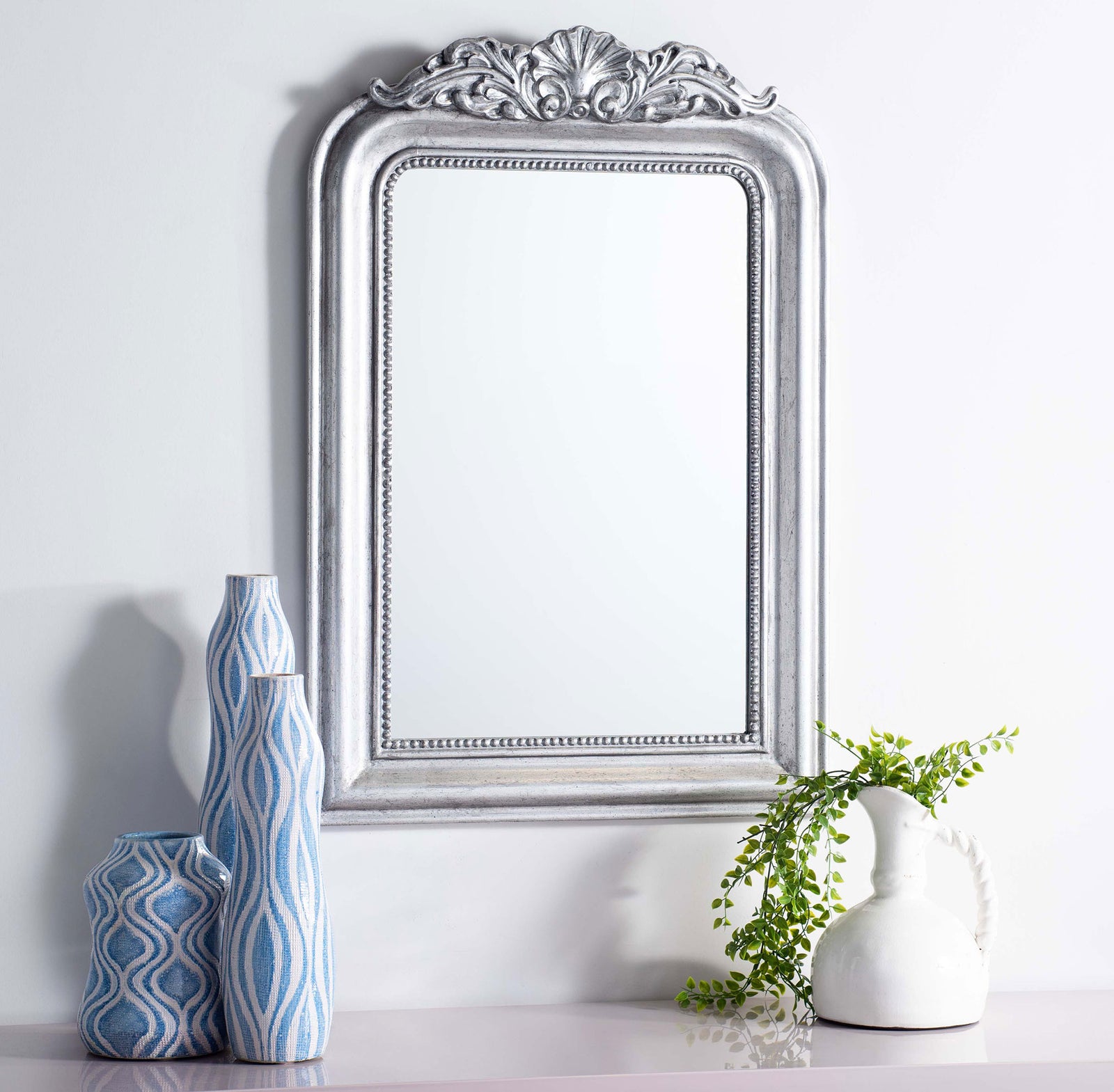 Antique silver mirror brings ornate detail to a wall above blue vases and greenery || MRR5000B || front_room