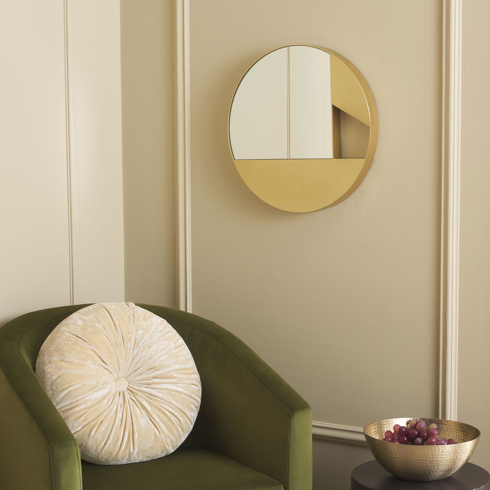 Round gold mirror adds geometric shine above an olive green chair || MRR8007A || front_room