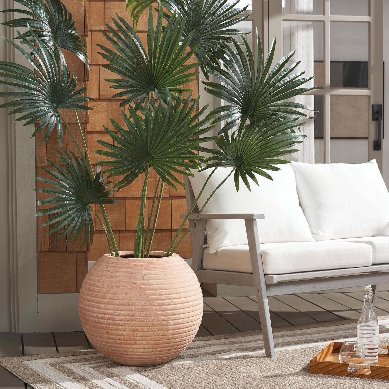 Ribbed terracotta planter brightens a tall fan palm with a warm, clay-toned finish. || PAT1534D || front_room