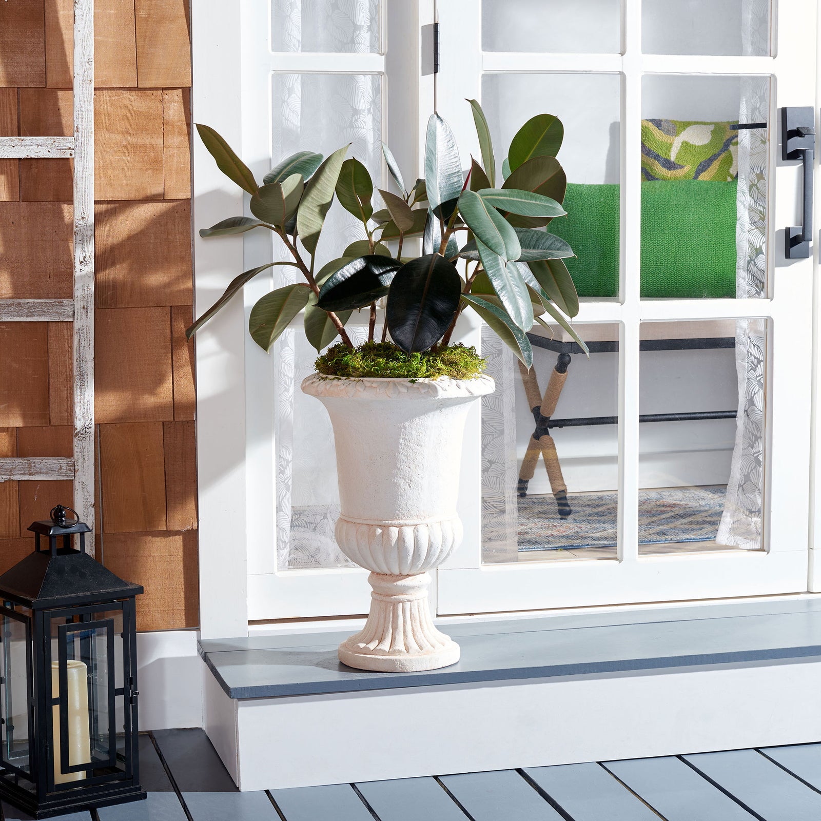 Off-white urn planter supports lush greenery against a bright doorway and warm wood siding. || PAT5037A || front_room