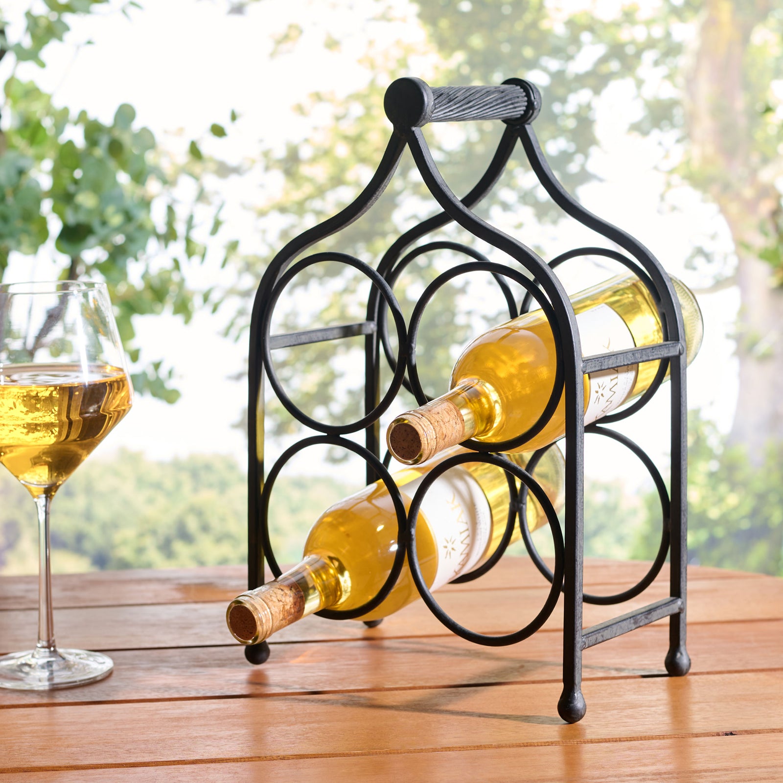 A black iron wine holder keeps bottles close at hand for outdoor gatherings. || PAT5041E || front_angle_room