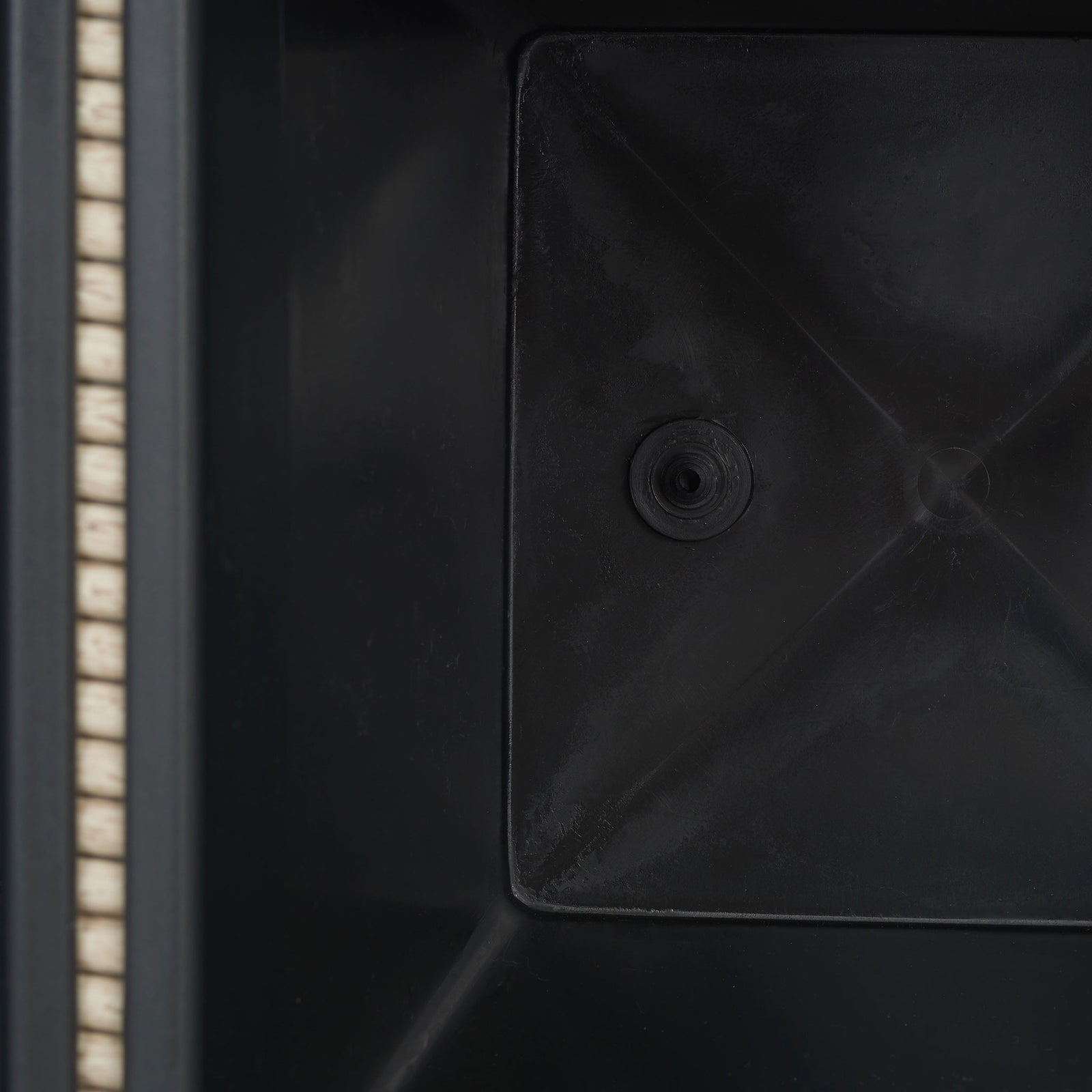 A molded black planting insert features a recessed circular drain opening. || PAT7705B || detail_studio