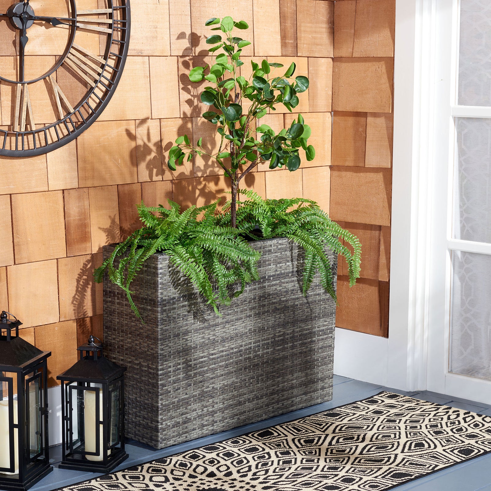 Lush greenery spills over a tall gray-brown wicker planter on the patio. || PAT7705C || front_room