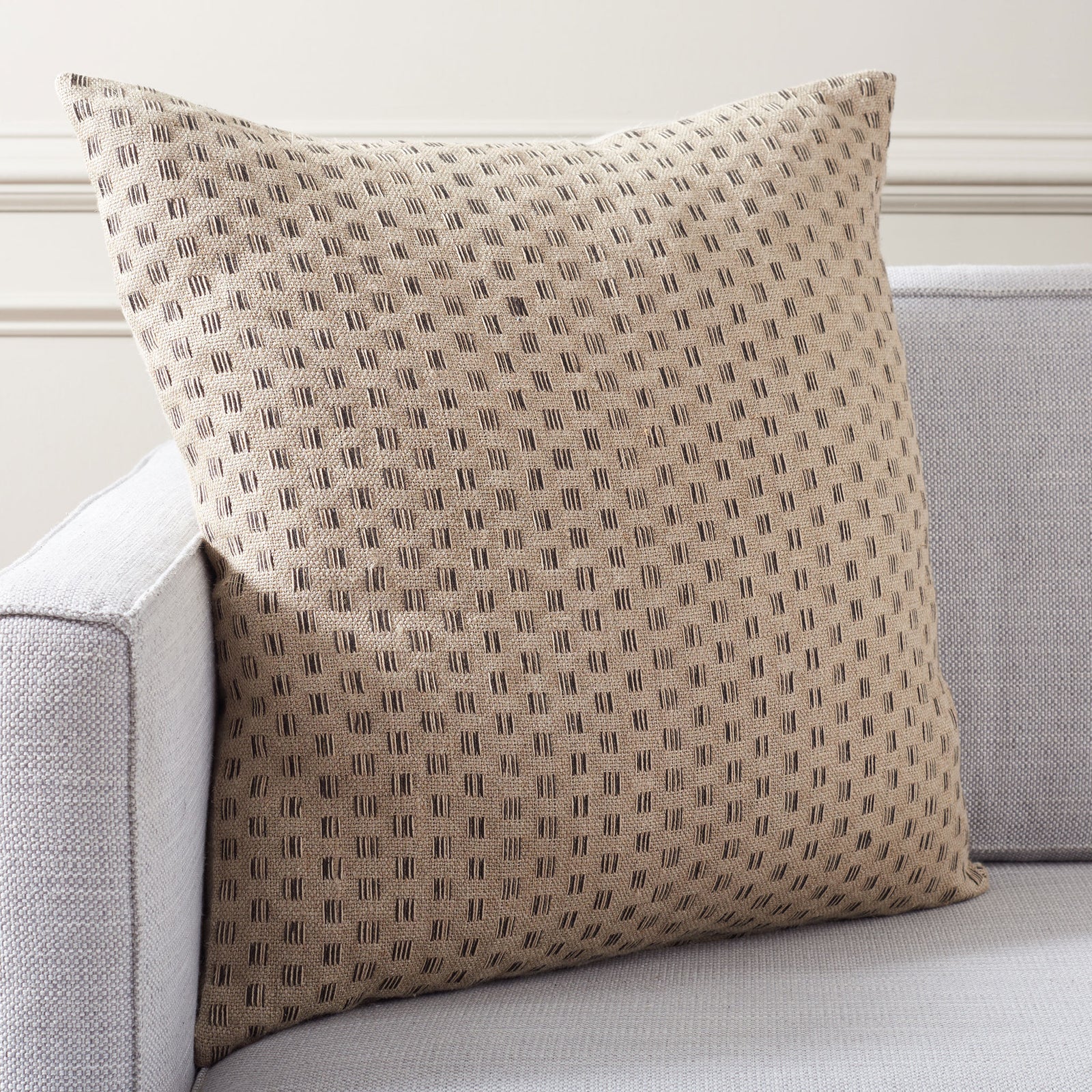 Natural linen square pillow with fine black dash motifs brings cozy contrast to a light-colored sofa. || PLS8011A-2424 || front_room