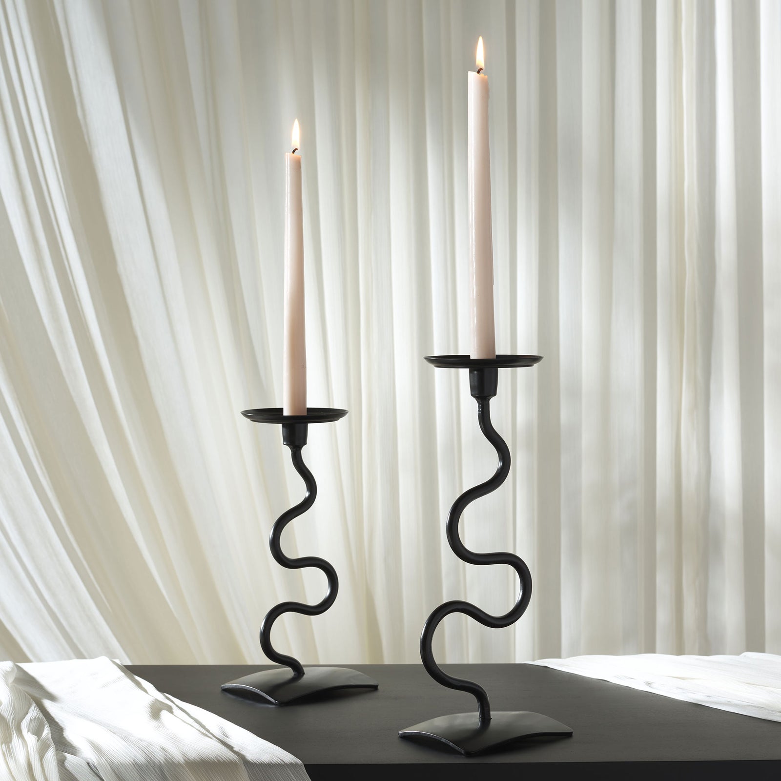 Lit tapers rise above two black, wavy candlesticks with elegant curved bases || RDC2502A-SET2 || front_room