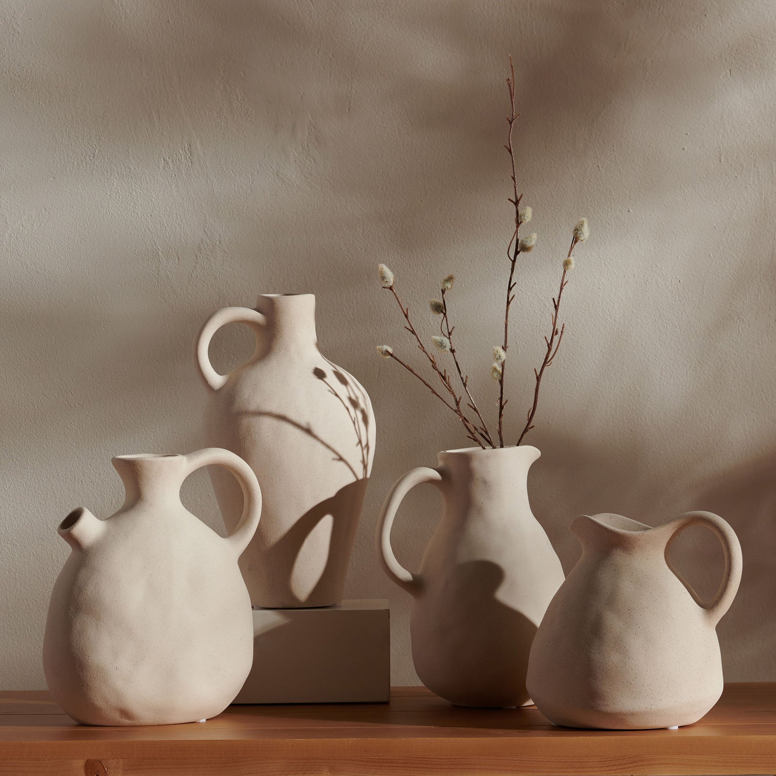 Four sculptural beige ceramic vases bring organic warmth to a tabletop with varied handles and rounded forms. || RDC4015A-SET4 || front_room