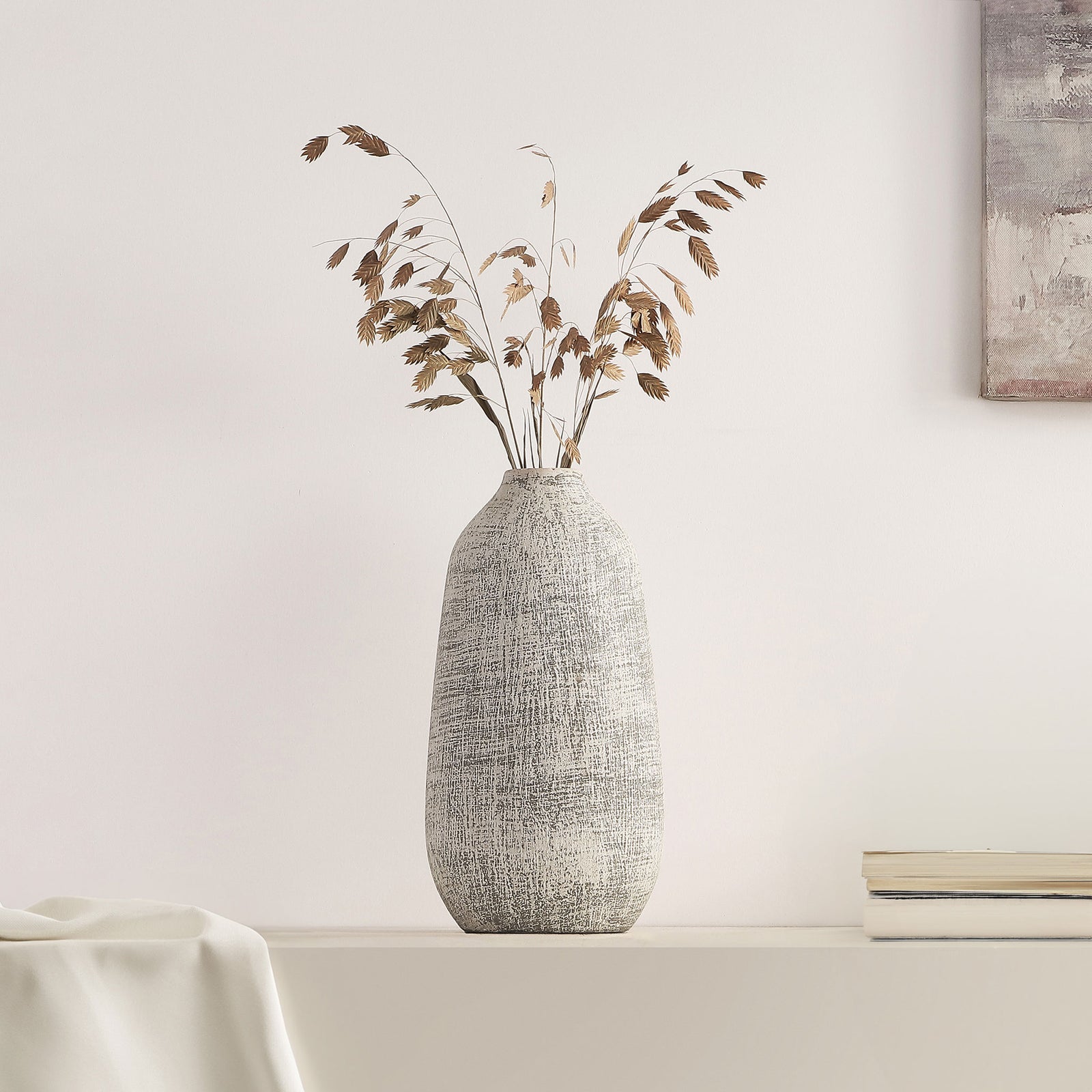 A whitewashed gray ceramic vase holds airy dried branches on a minimalist shelf || RDC4031A || front_room