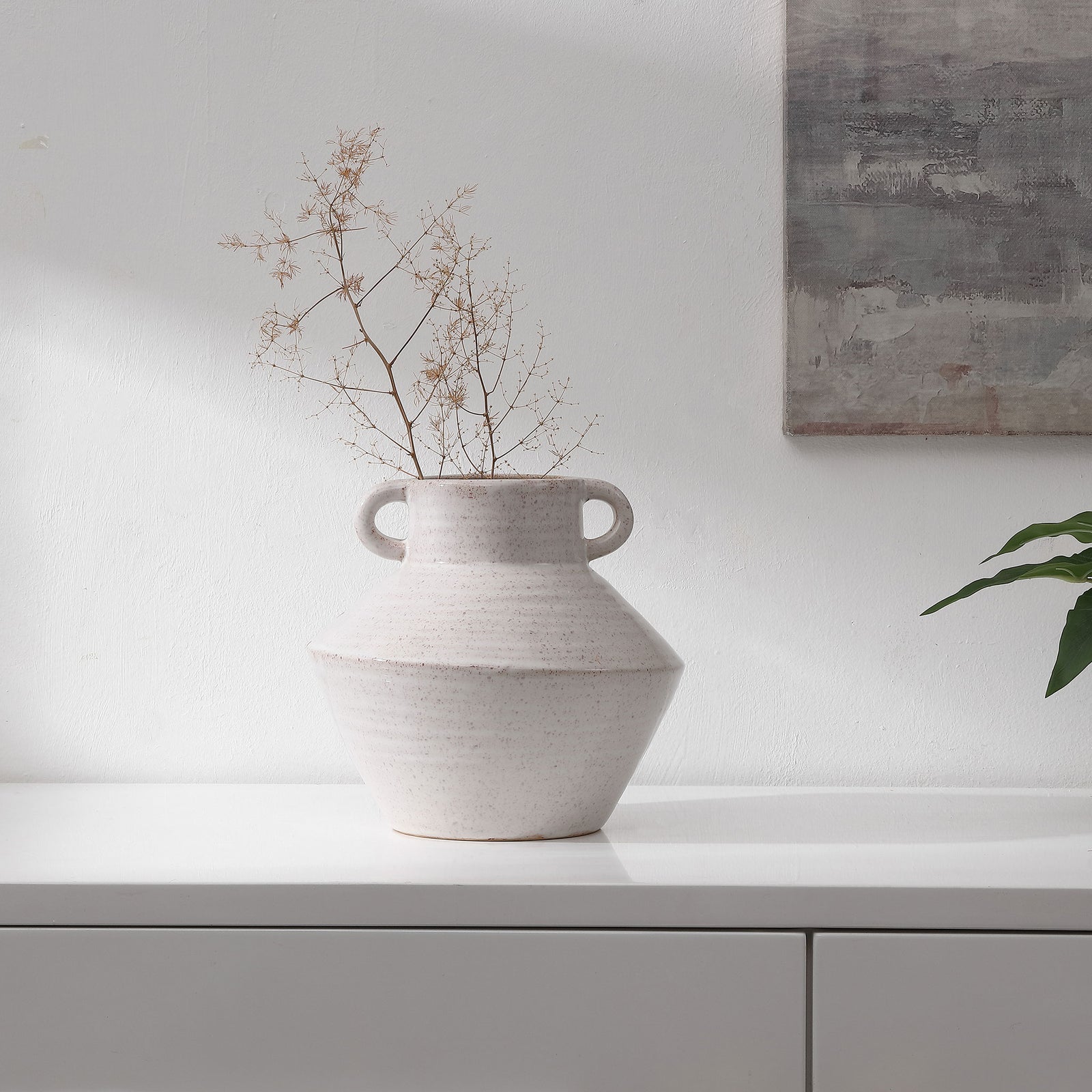 Delicate dried stems rise from a speckled ceramic vase, bringing an organic accent to the room. || RDC4046A || front_room