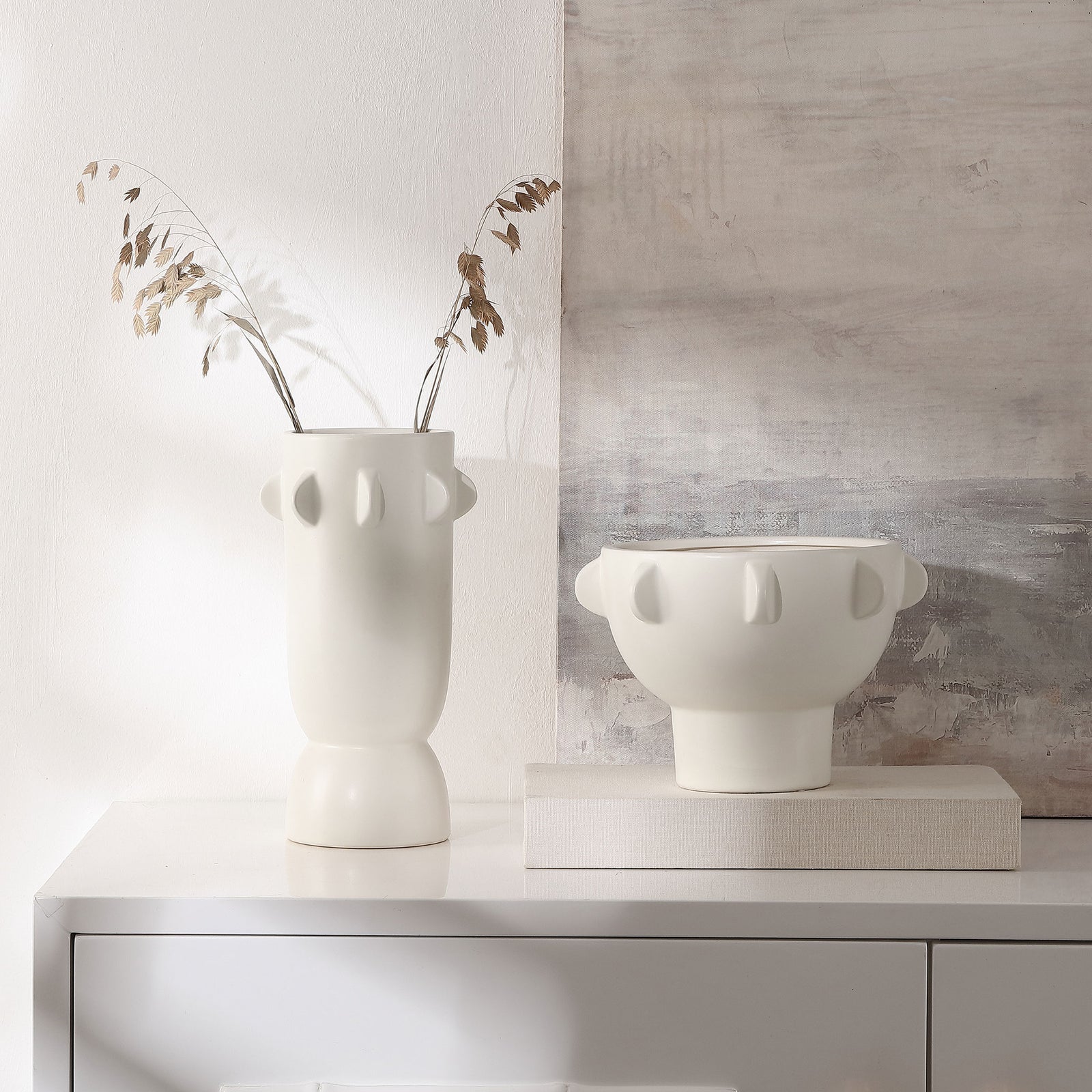 A tall vase holds dried stems beside a low, wide bowl, bringing soft texture to a modern console. || RDC4047A-SET2 || front_room