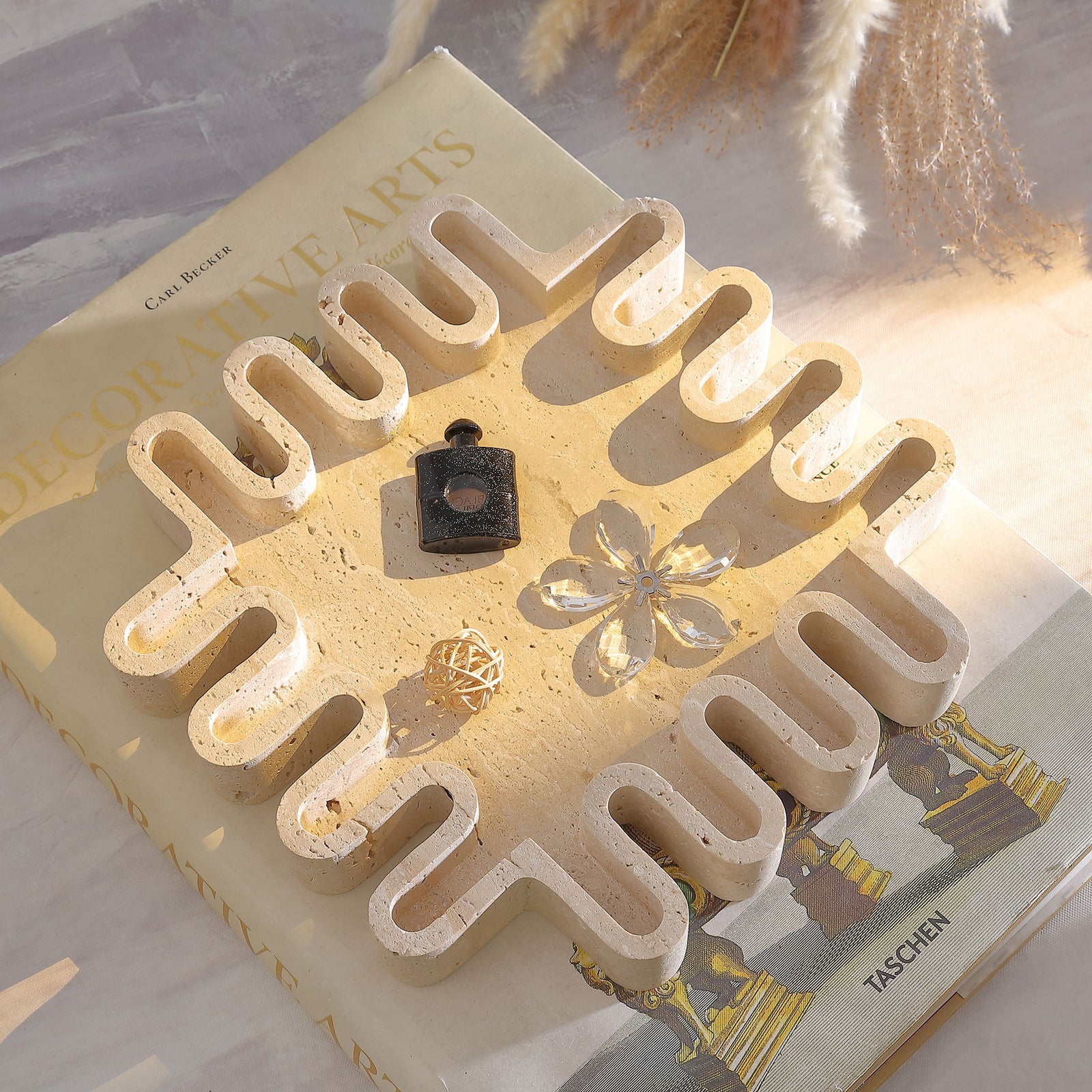 Tan travertine tray displays small keepsakes within its sculptural, wavy-edged square form. || RDC4055A || top_angle_room
