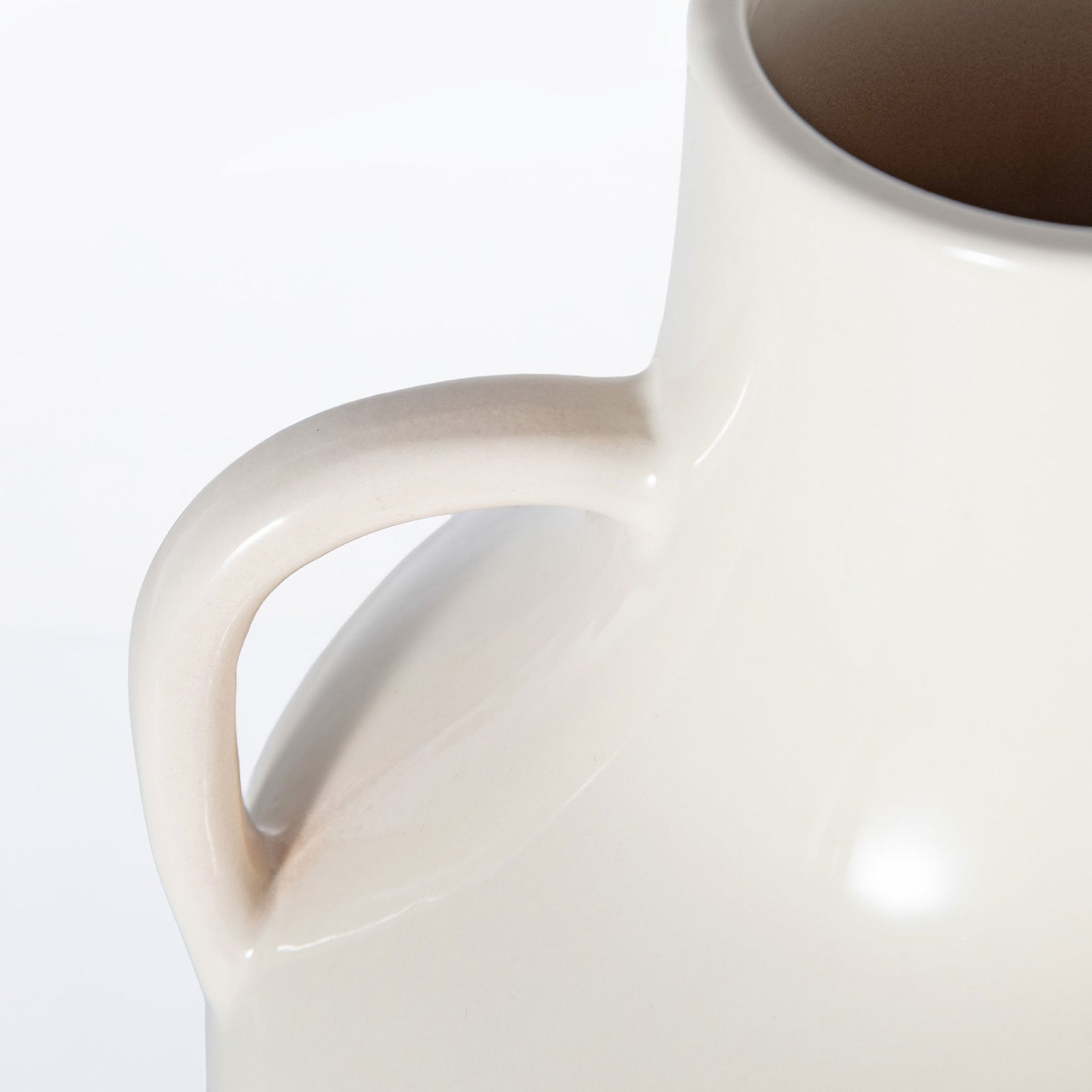 A sculpted loop handle blends into the glossy ivory ceramic body beneath the open rim. || RDC4062A || handle_studio