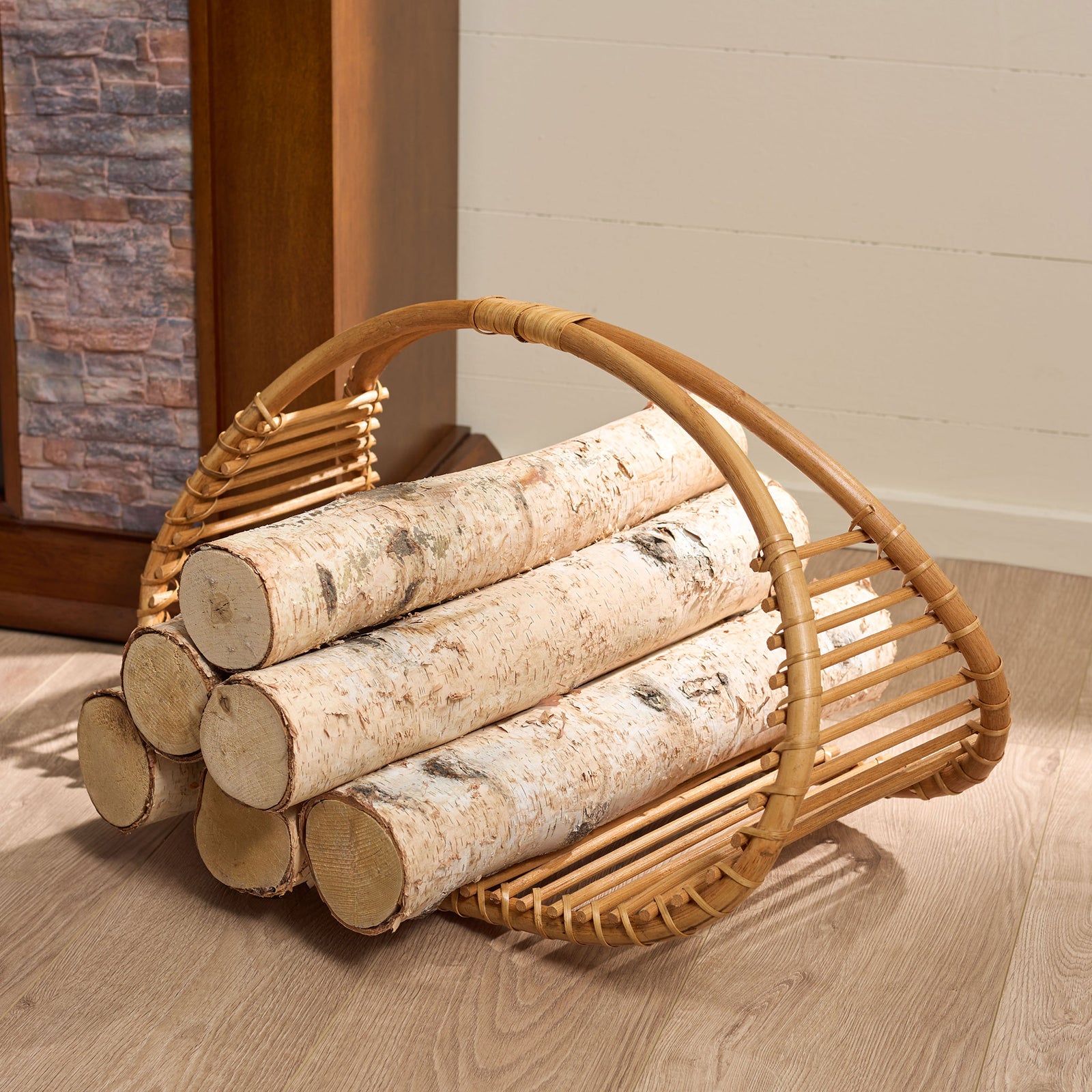 The larger slatted rattan basket cradles stacked logs beside the fireplace. || STG1819A || front_angle_partial_room