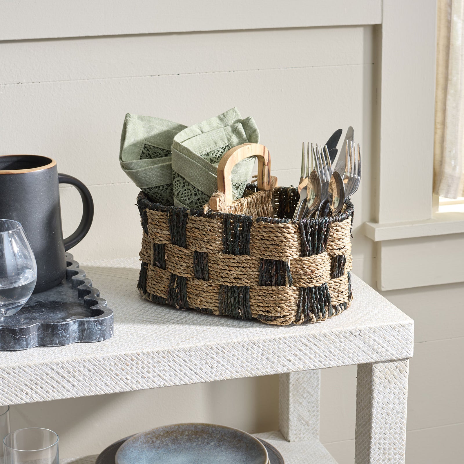 Two-tone woven basket keeps napkins and flatware together on a tabletop. || STG1821A || front_angle_room