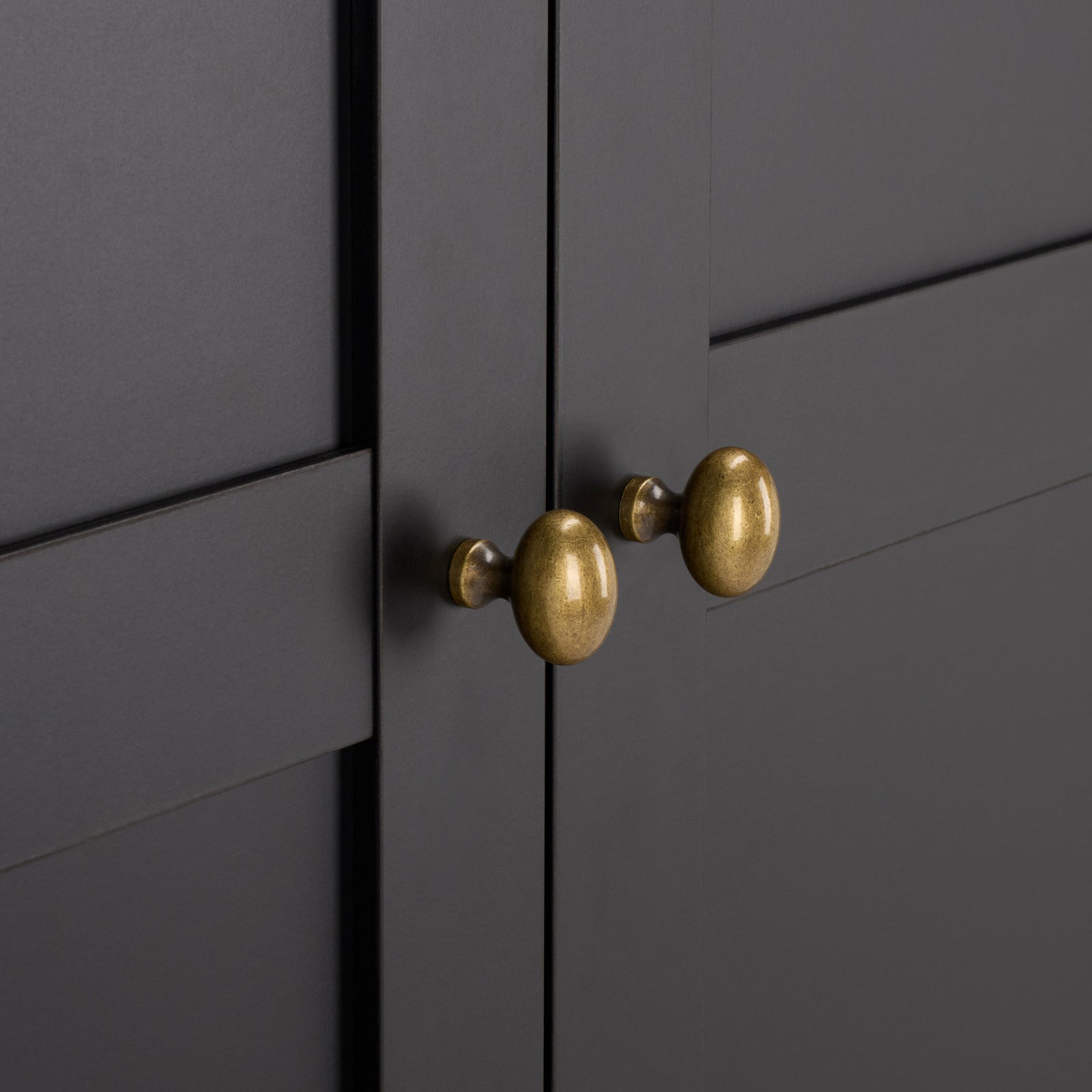 Softly rounded brass-tone knobs add a warm accent to sleek black paneled doors. || STG3103C-3BX || handle_studio
