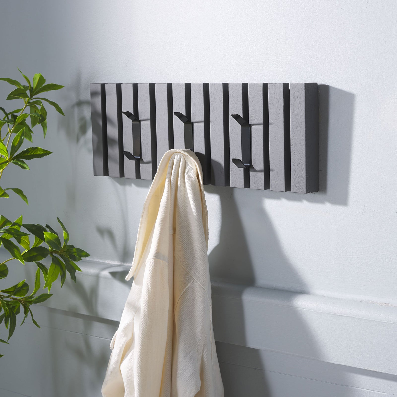 A cream robe hangs from the gray wood rack, with two free hooks for more everyday layers. || STG5704A || front_angle_room