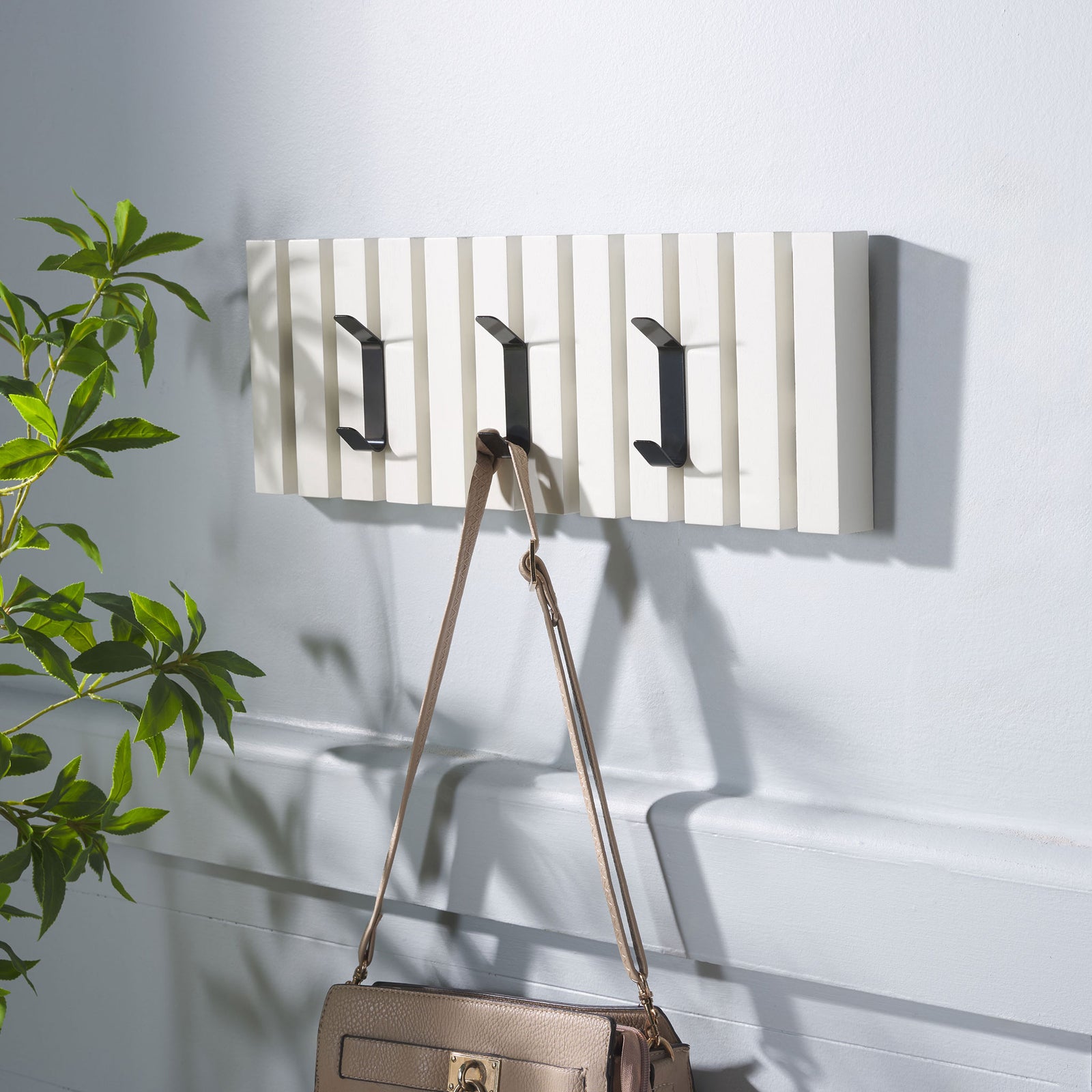 A handbag hangs from the white slatted rack, while two more black hooks stand ready for coats and hats. || STG5704C || front_angle_room