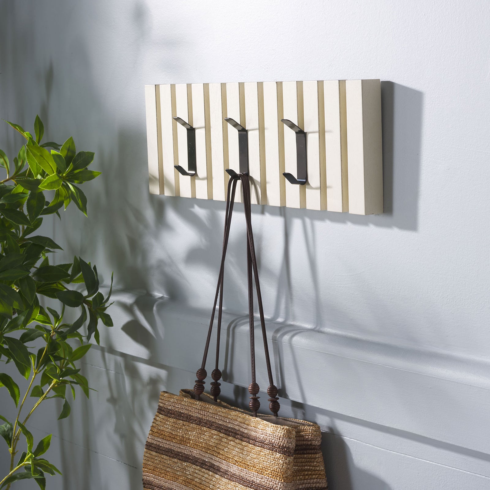 A woven bag hangs from the distressed white slatted rack, with room on its other hooks for more. || STG5704L || front_angle_room