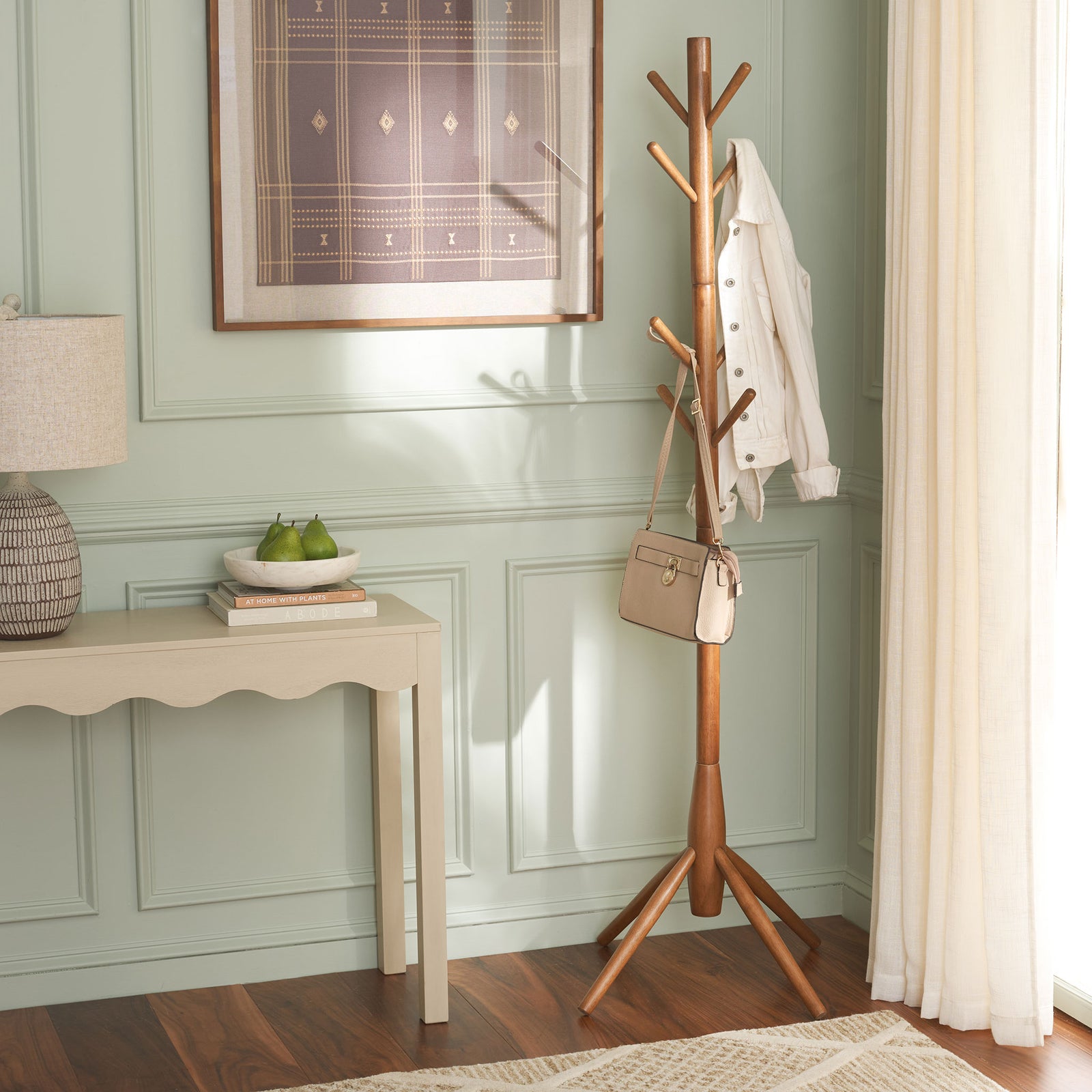 Honey wood coat stand holds a jacket and handbag beside a light console table || STG8500D || front_room