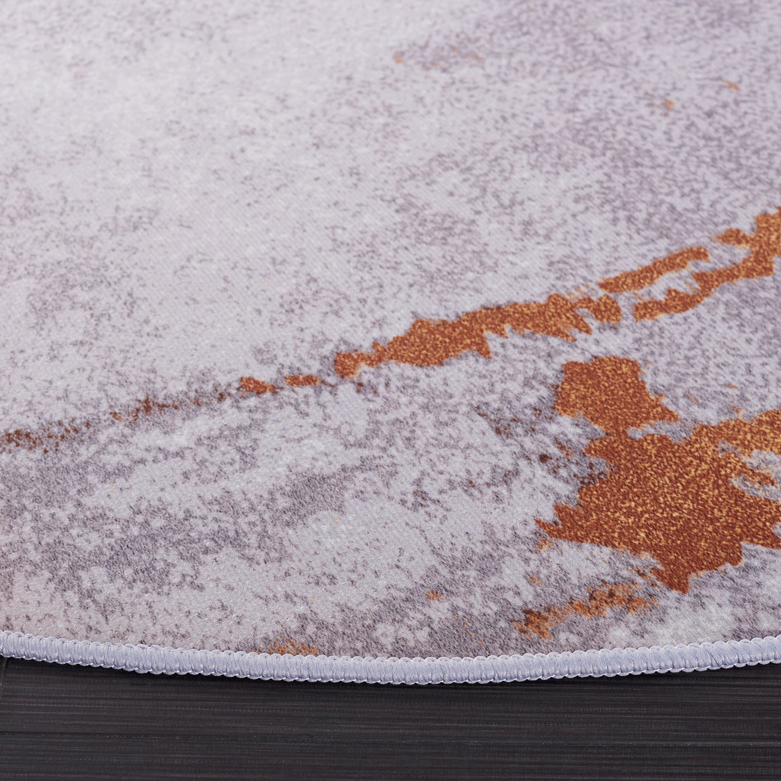 Stitched edge and softly textured pile highlight the gray and rust abstract pattern. || TAC801P-6R || corner_studio