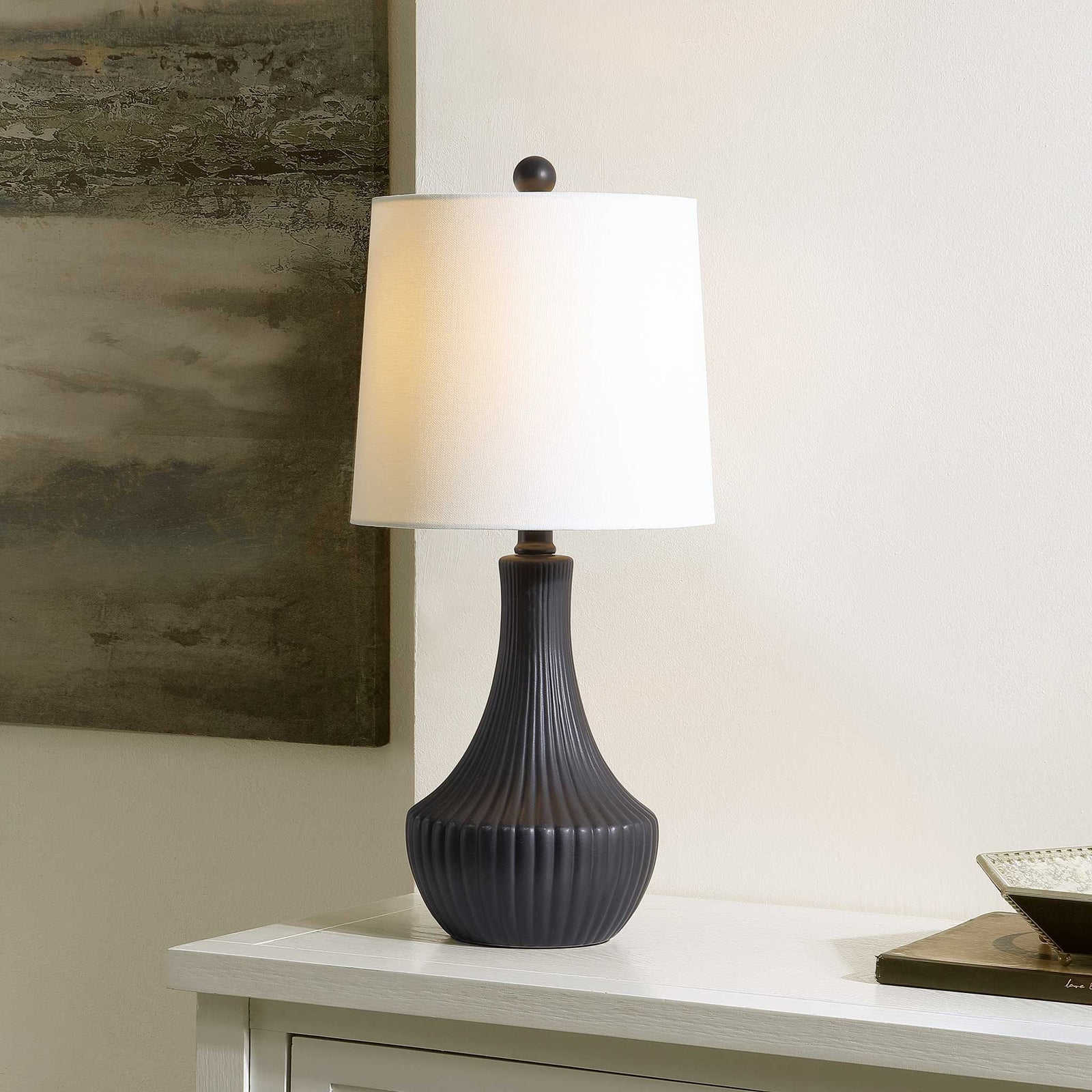 Warm glow highlights the ribbed black base and clean white shade for a cozy, modern accent || TBL4479A || front_angle_on_room