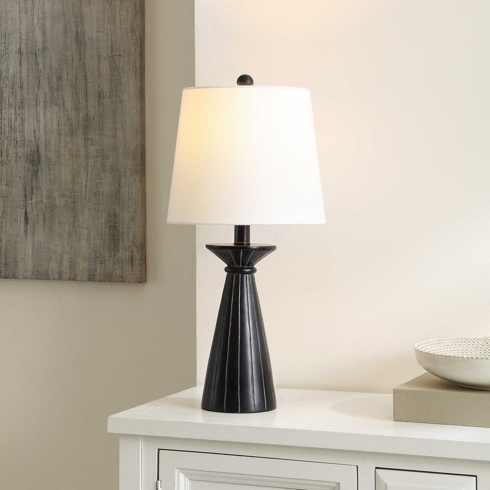 Illuminated white shade casts a cozy glow above a fluted black base for inviting, modern style. || TBL4485A || front_angle_on_room