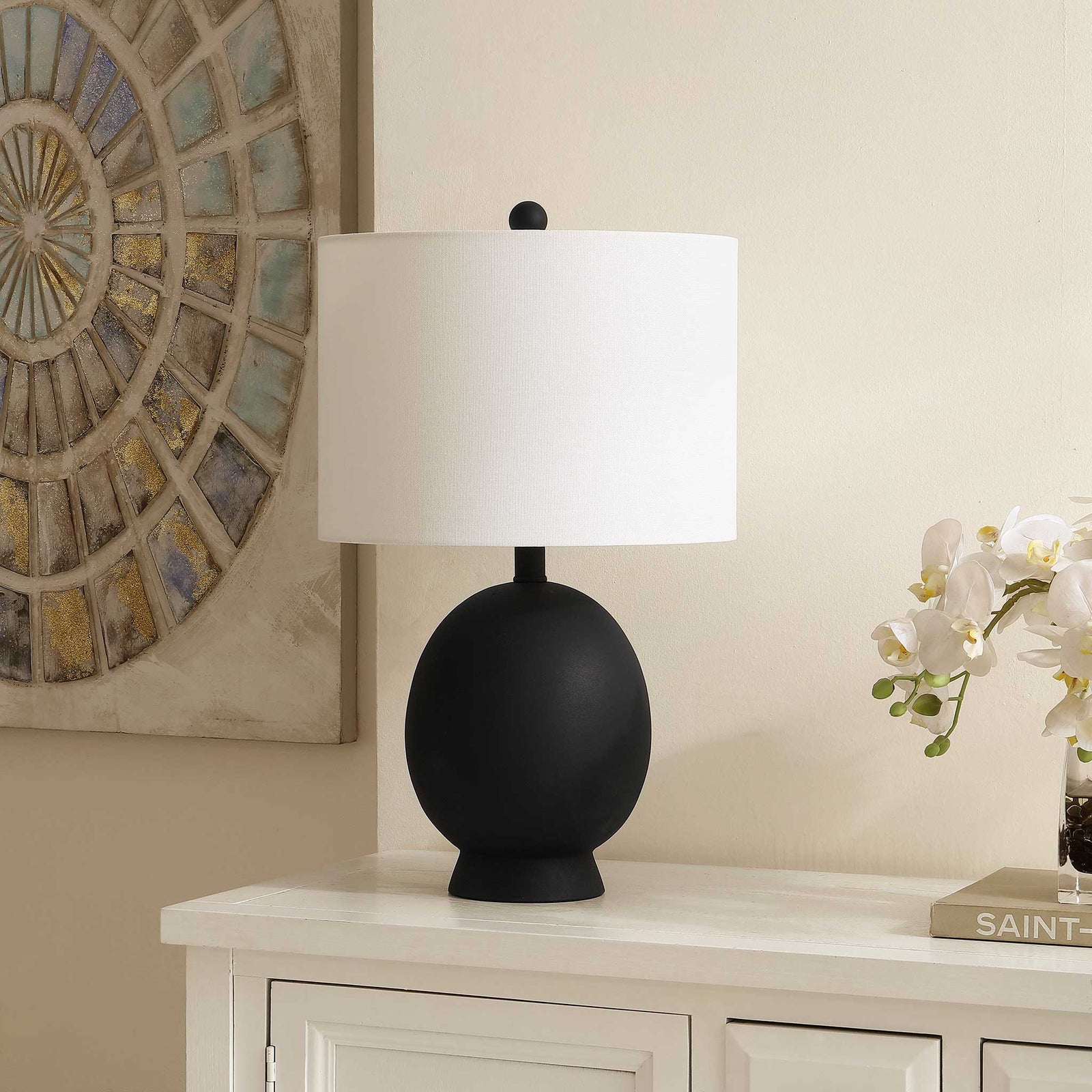 Matte black oval lamp with white shade adds a refined touch on a console in a neutral living space. || TBL4487A || front_angle_room