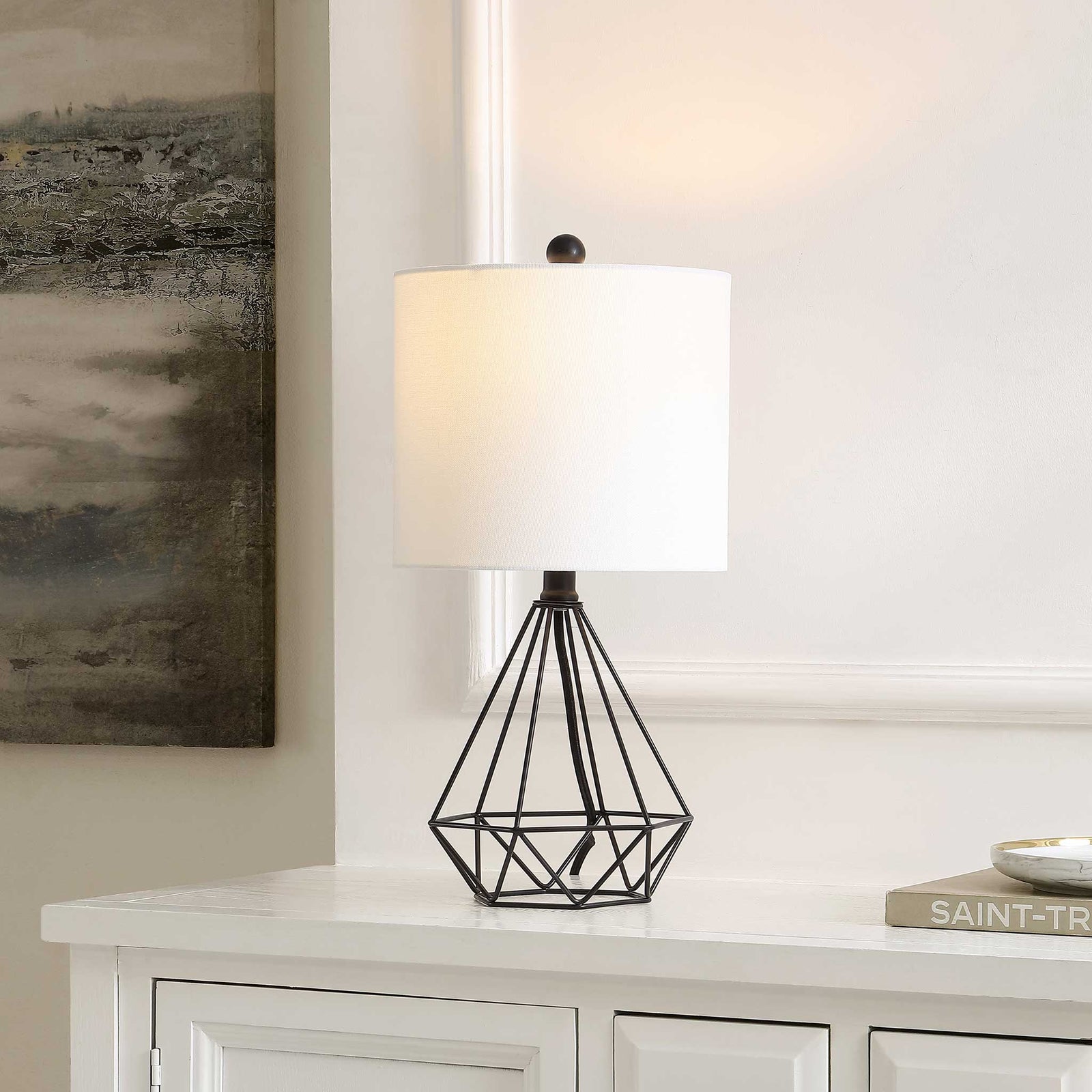 Soft ambient light glows from a white shade atop a faceted black wire base for sleek, modern warmth. || TBL4489A || front_angle_on_room