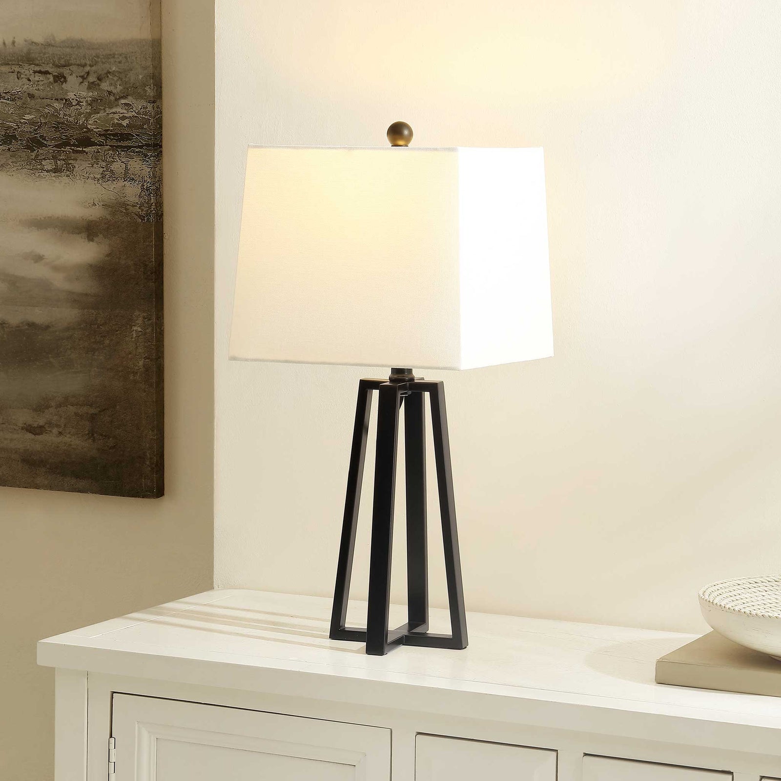 Soft, ambient glow from a white shade crowns the black iron base, elevating contemporary decor with warmth. || TBL4505A || front_angle_on_room