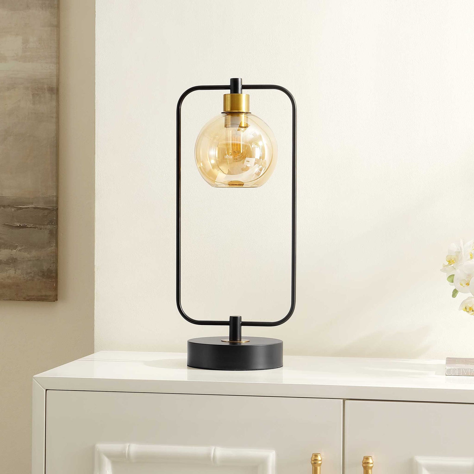 Modern lamp adds sculptural style with a black frame and amber globe on a crisp console || TBL4524A || front_angle_room