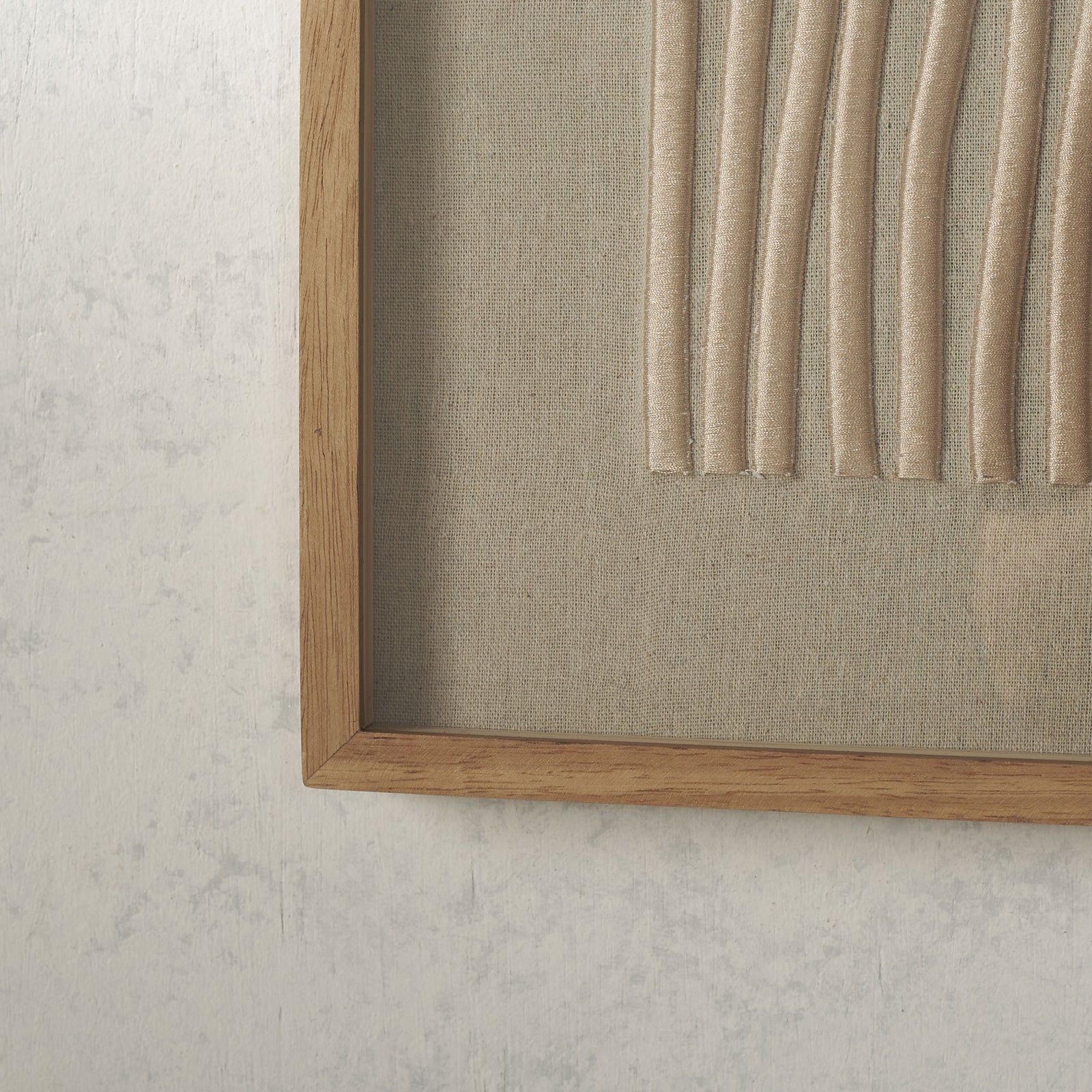 The lower edge of raised beige embroidery meets textured linen inside a natural wood frame || WLA1905A || detail_room