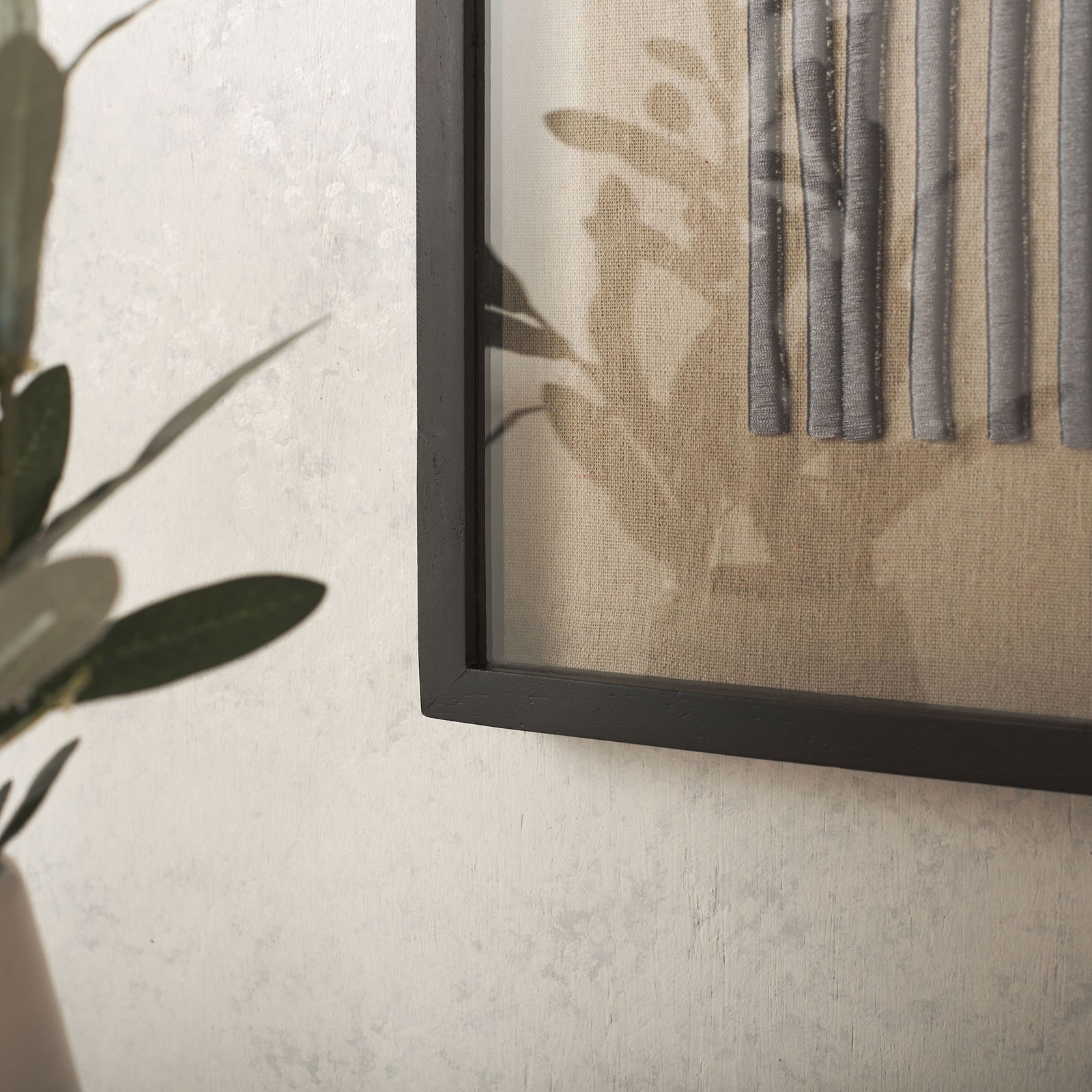 Raised gray-purple embroidery adds texture to natural linen within a slim black frame. || WLA1906A || detail_room