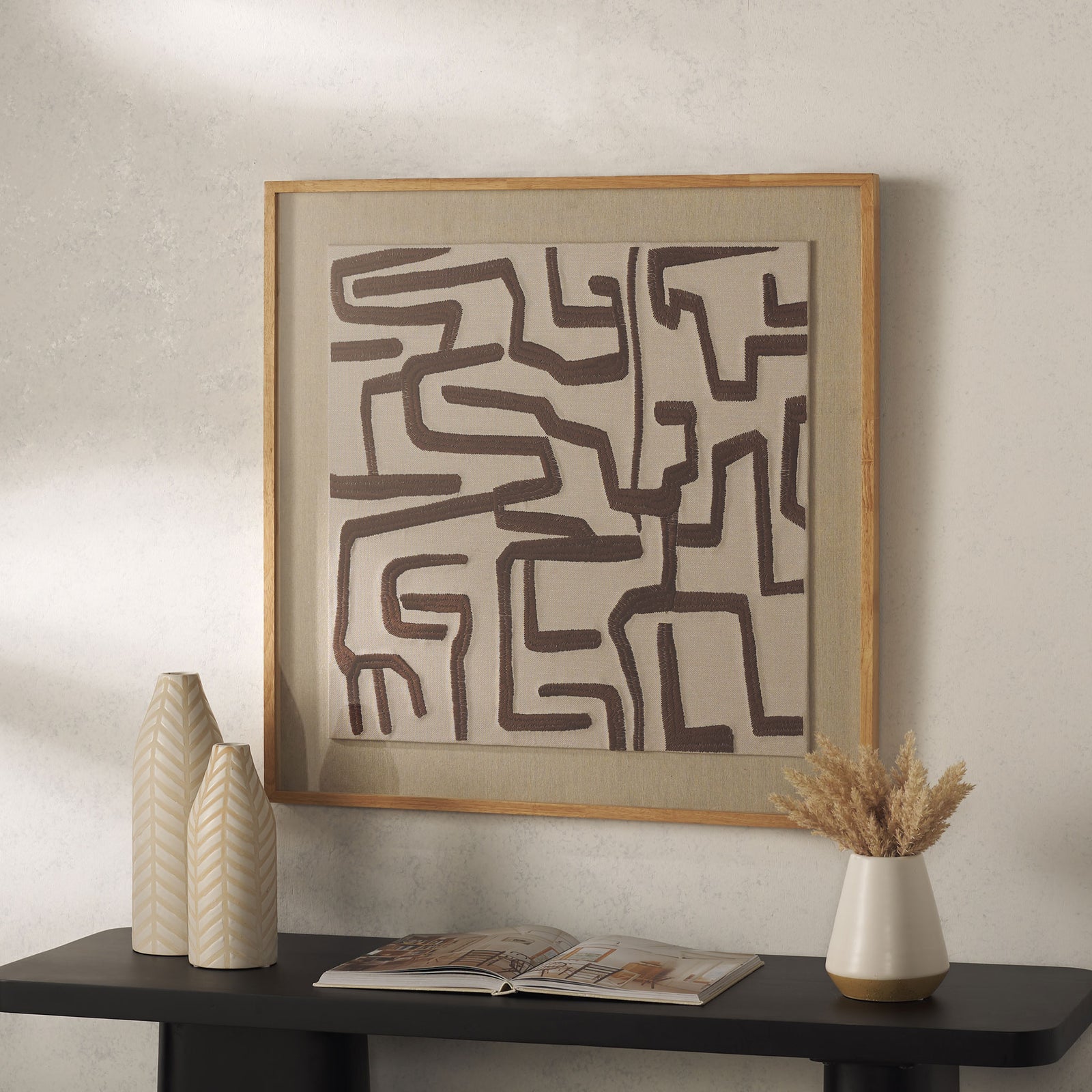 Ivory textile art with chocolate brown geometric lines and a light wood frame adds warmth above a console || WLA1907A || front_room