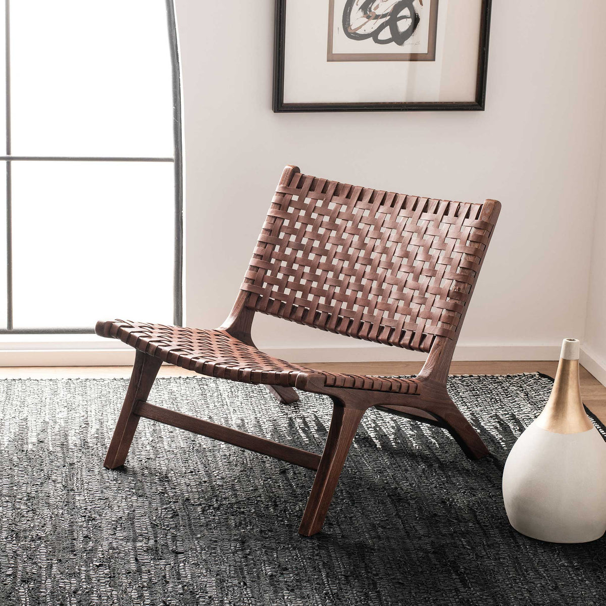 Cognac leather webbing lends welcoming warmth to a low accent chair on a patterned rug.