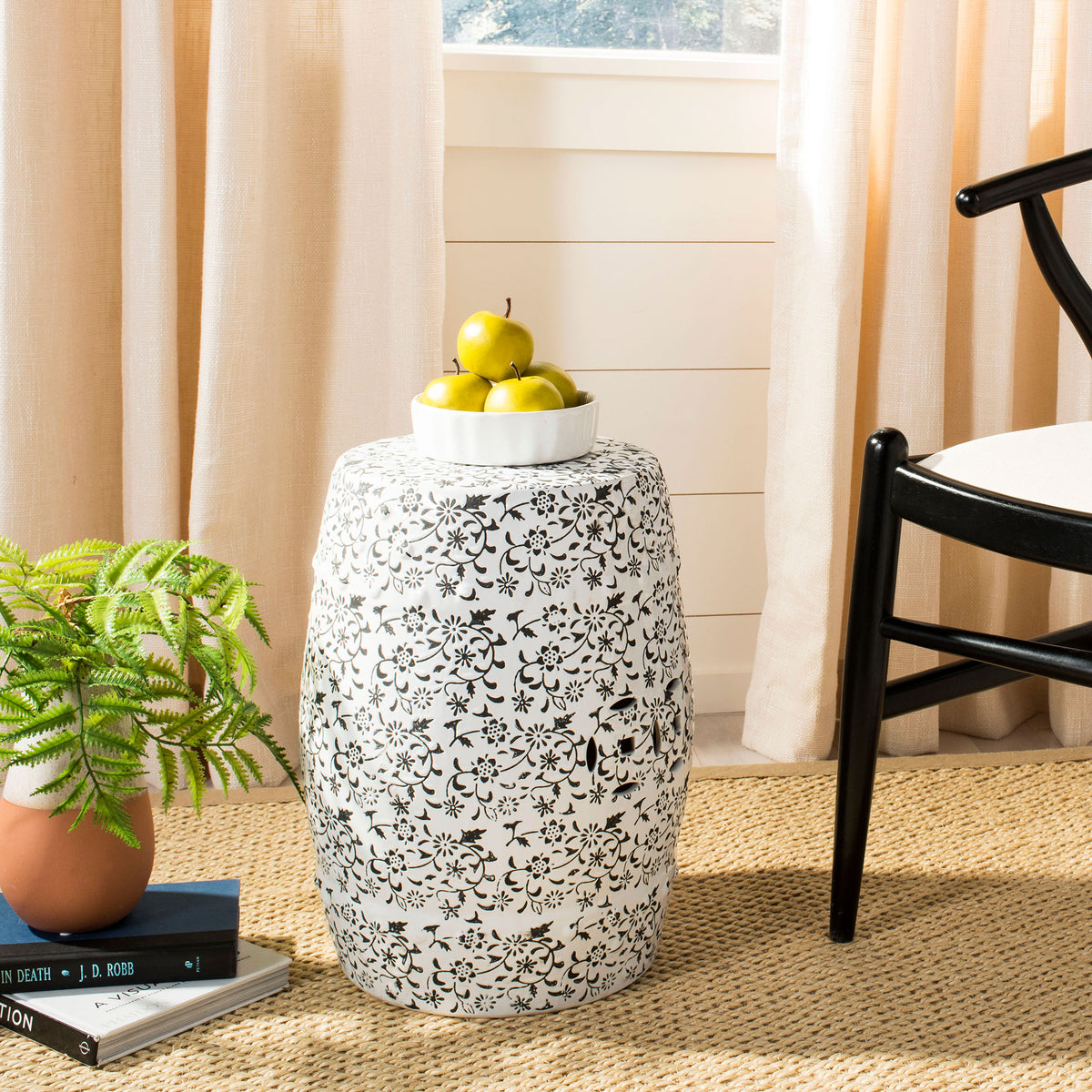 A white ceramic garden stool with floral vines serves as a decorative side table.