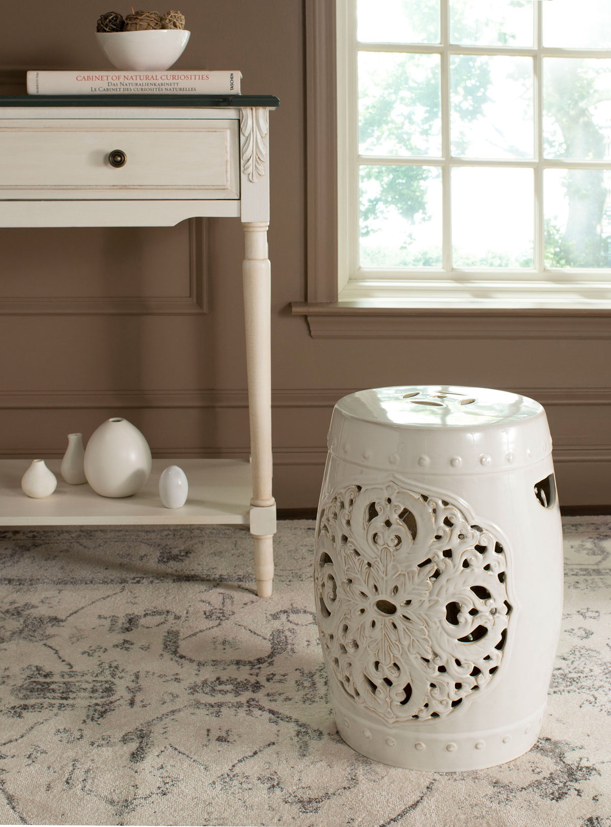 A cream ceramic stool pairs a smooth rounded top with airy floral cutouts. || ACS4527B || front_angle_room