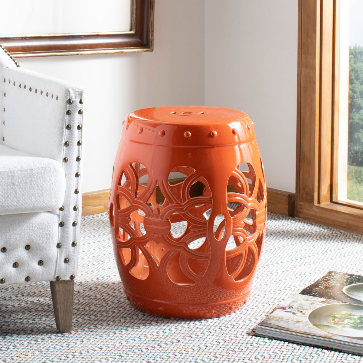 Orange ceramic garden stool adds a bold pop of color beside a cushioned chair || ACS4539D || front_angle_room