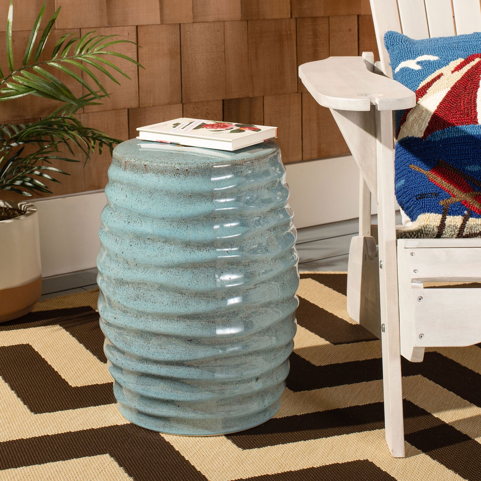 Glossy, light blue ribbed ceramic stool holds books beside a white lounge chair. || ACS4575B || front_angle_room