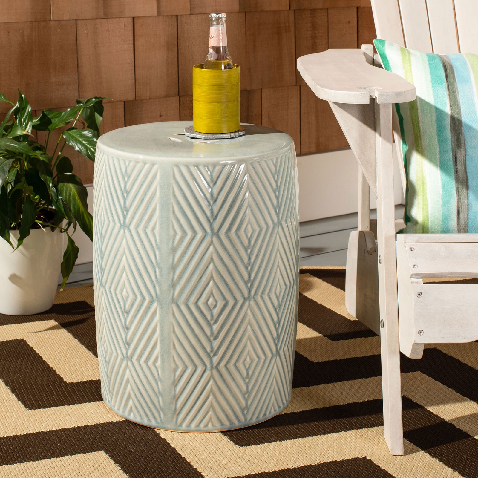 A blue ceramic garden stool with geometric relief makes a convenient drink table beside a patio chair. || ACS4578A || front_angle_room