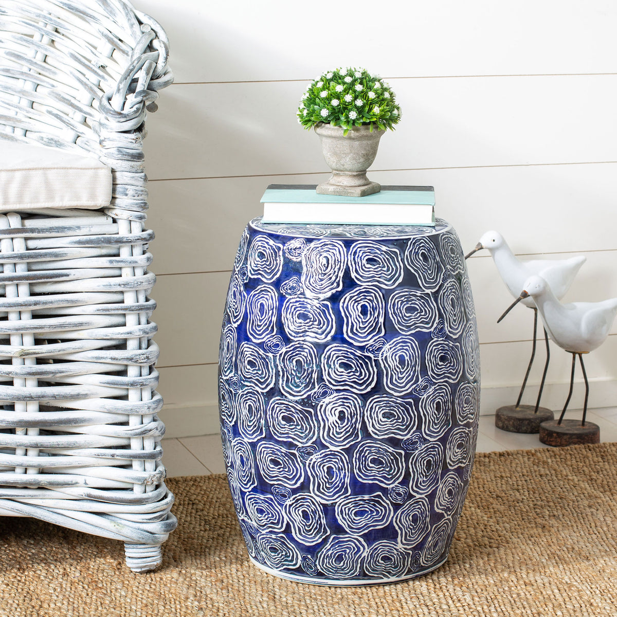 Blue and white ceramic garden stool doubles as a side table for books and a potted plant
