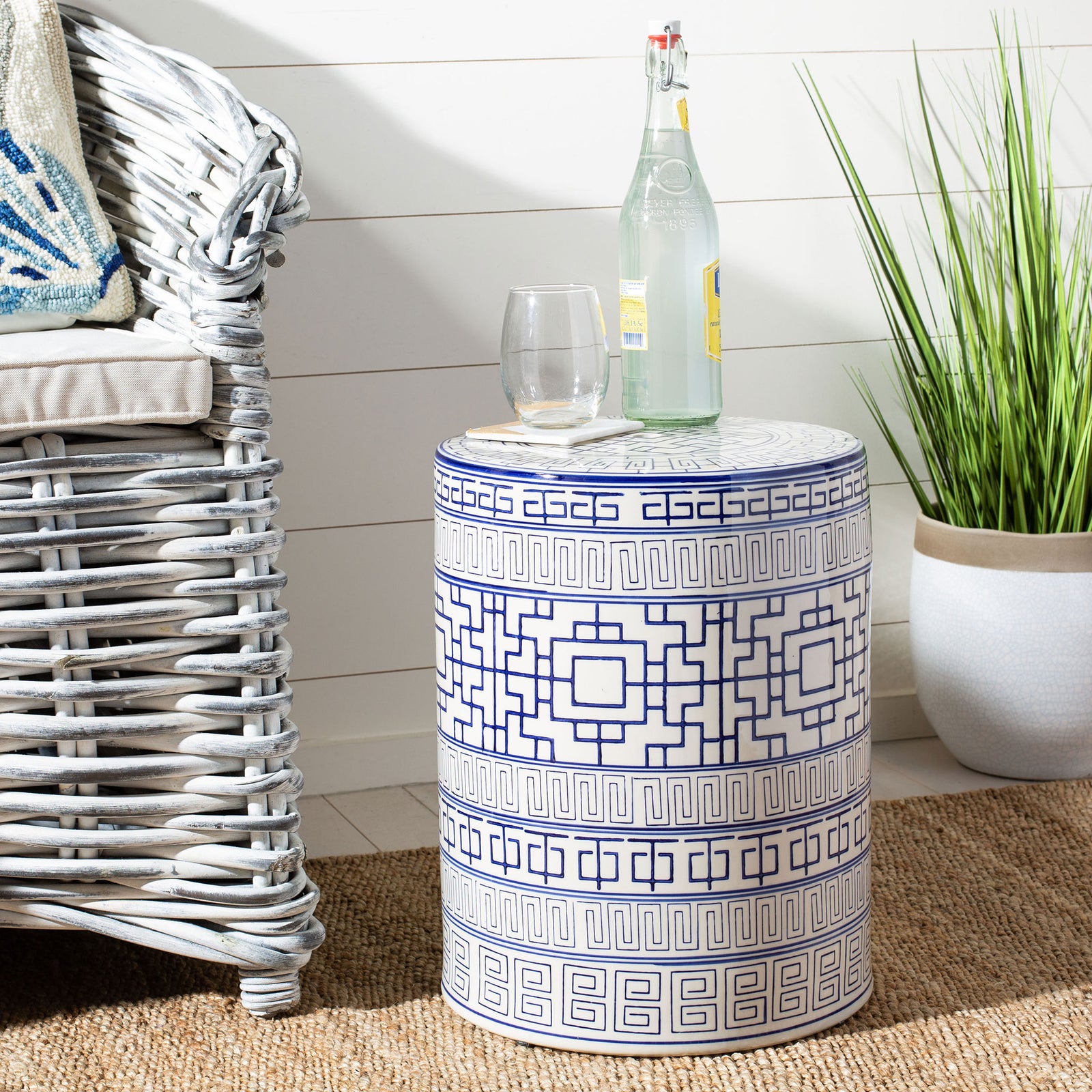Blue and white patterned ceramic garden stool doubles as a side table beside a woven chair || ACS4581A || front_angle_room