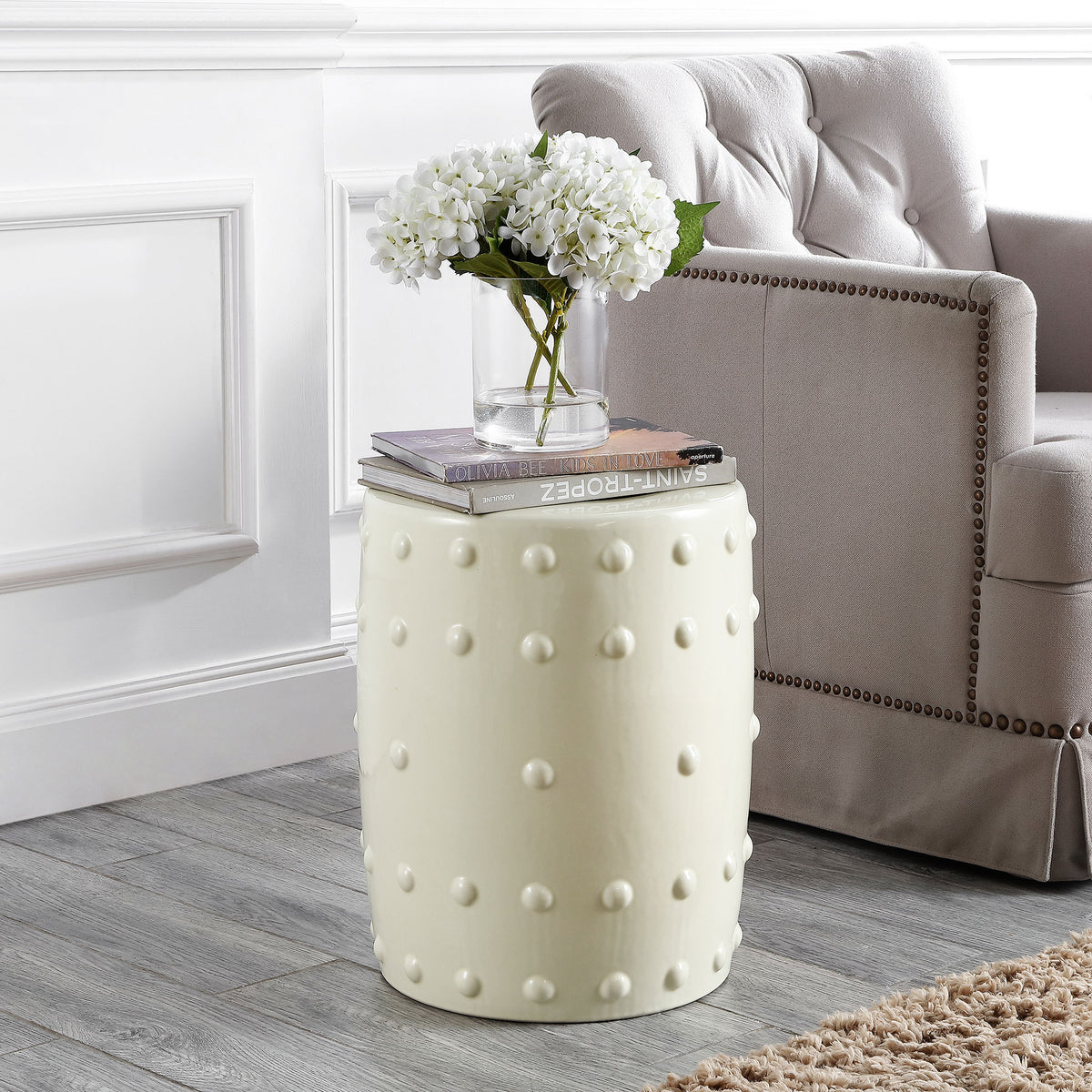Cream ceramic garden stool with raised dots doubles as a side table beside a plush chair || ACS4590A || front_angle_room