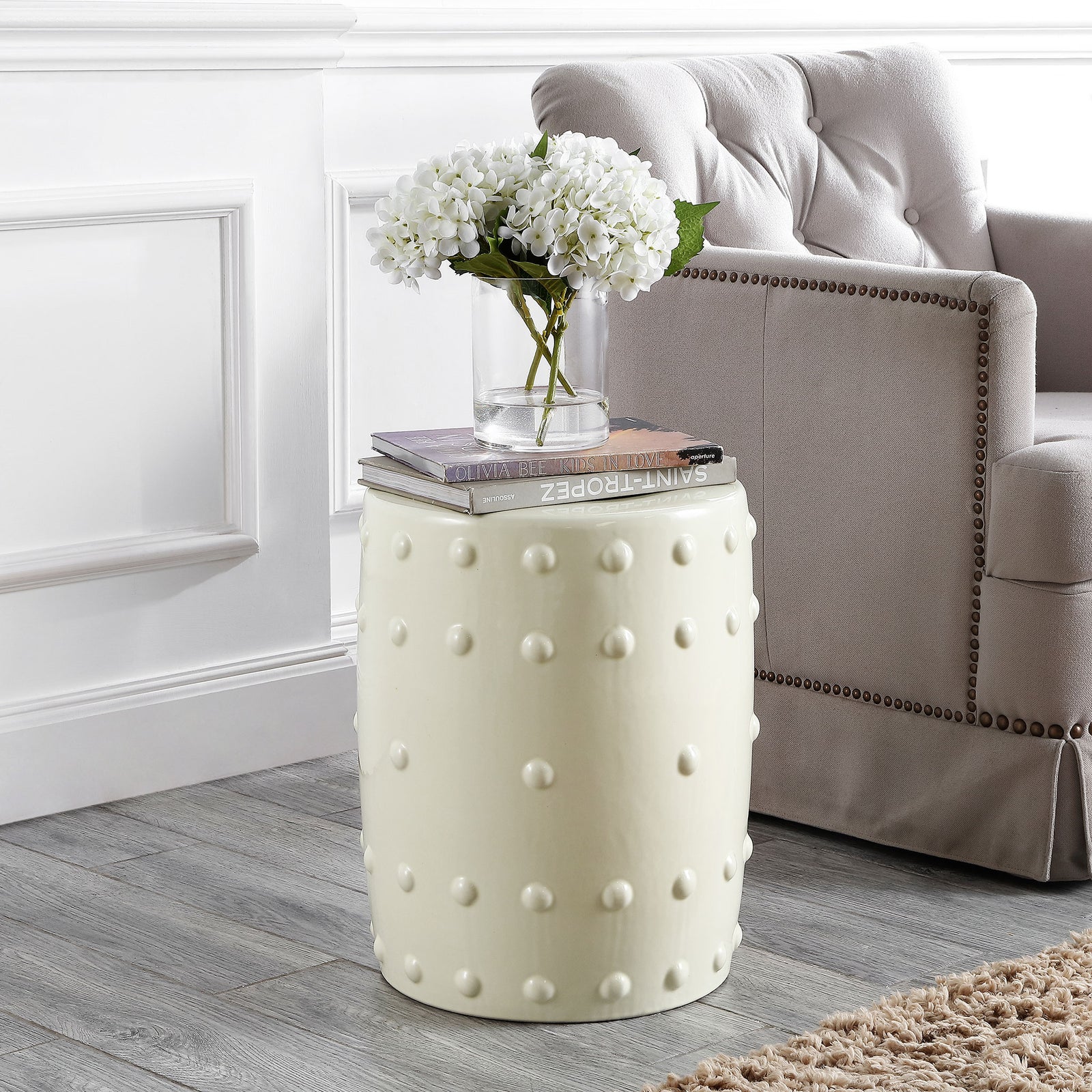 Cream ceramic garden stool with raised dots doubles as a side table beside a plush chair || ACS4590A || front_angle_room