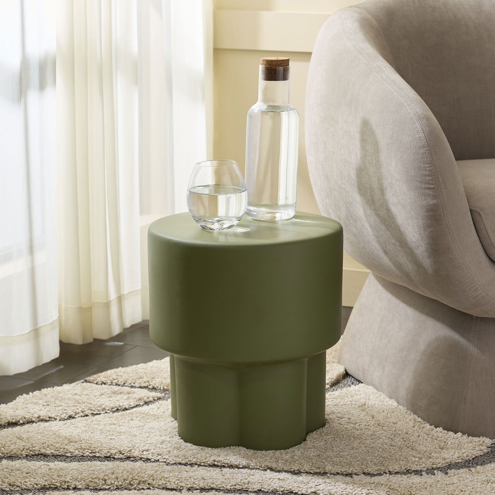 Moss green ceramic stool holds a drink and carafe beside an upholstered chair || ACS4593D || front_room