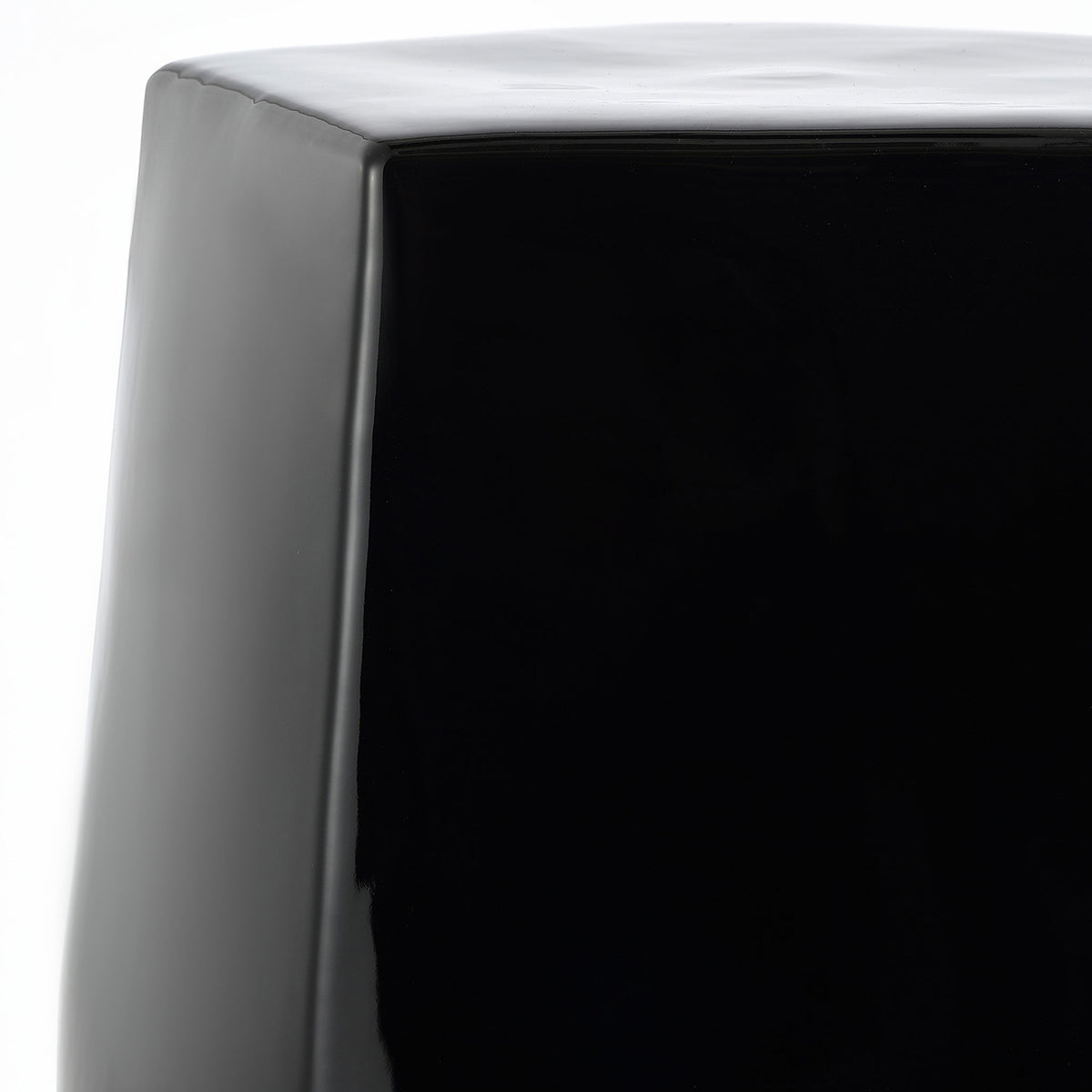 A smooth, rounded edge frames the black ceramic stool's flat top