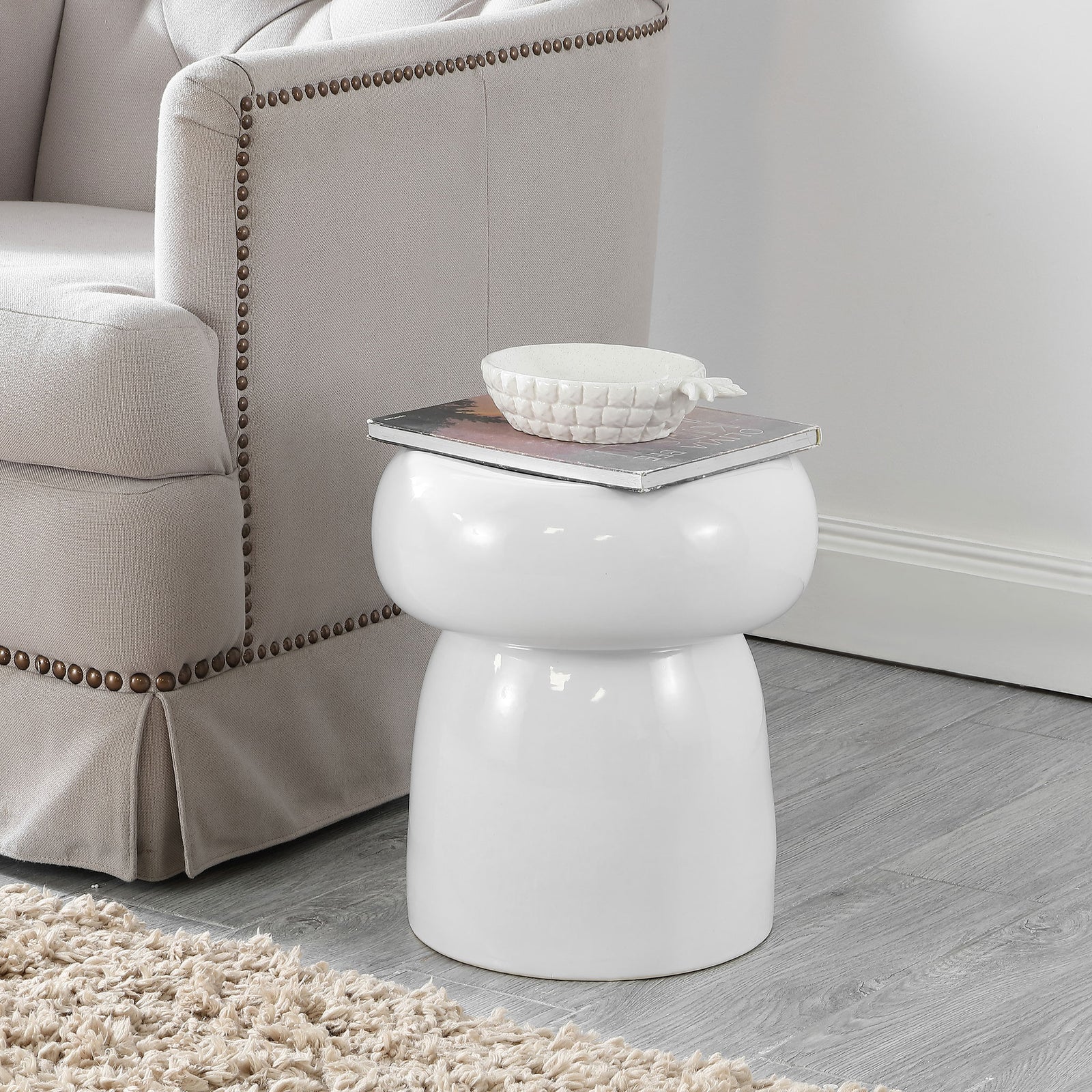 The white ceramic garden stool adds a compact side-table surface beside a cozy chair. || ACS4598A || front_room