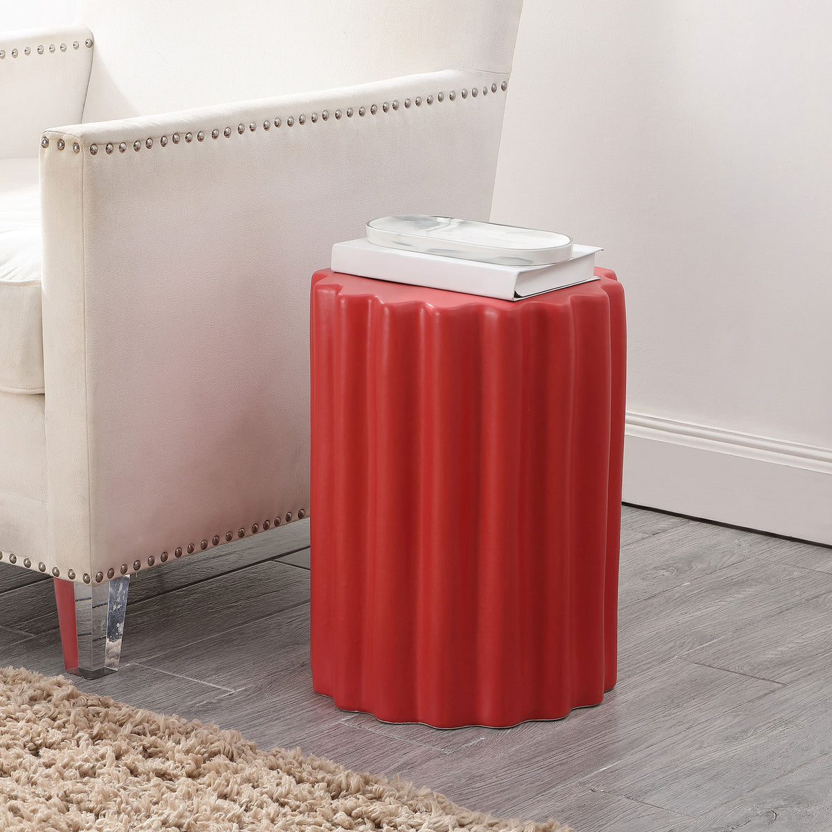 Bright red fluted ceramic stool doubles as a side table next to an upholstered chair || ACS4600F || front_angle_room
