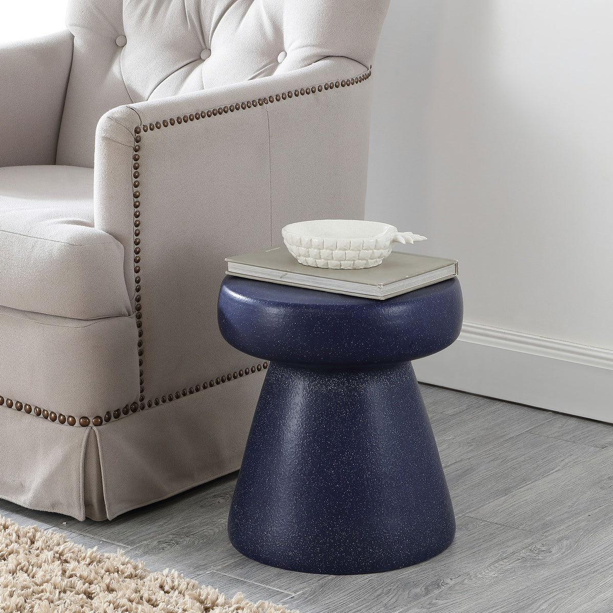Navy speckled ceramic stool provides a rich accent beside an upholstered armchair