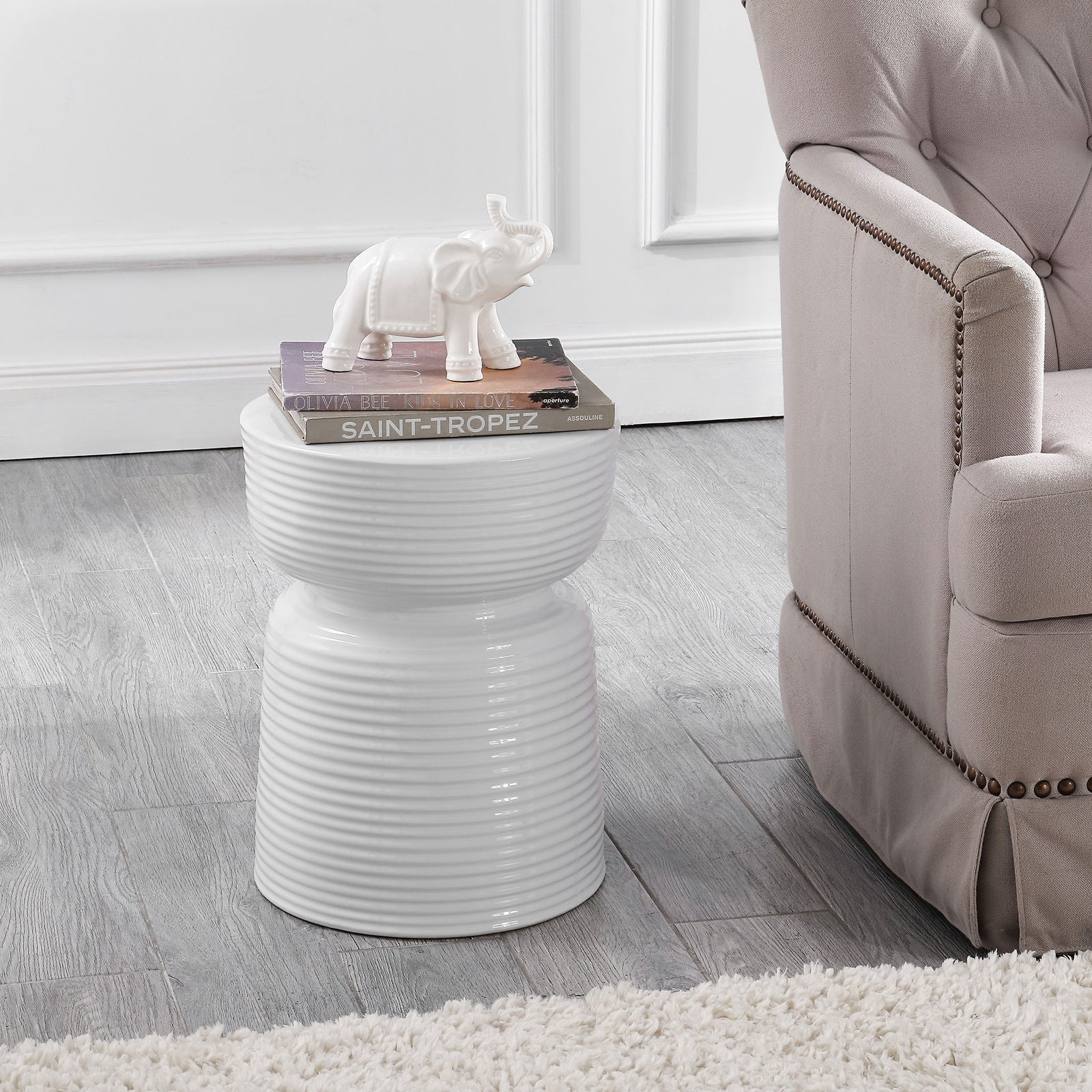 White ribbed ceramic stool holds books and serves as a side table beside a tufted chair || ACS4605A || front_room